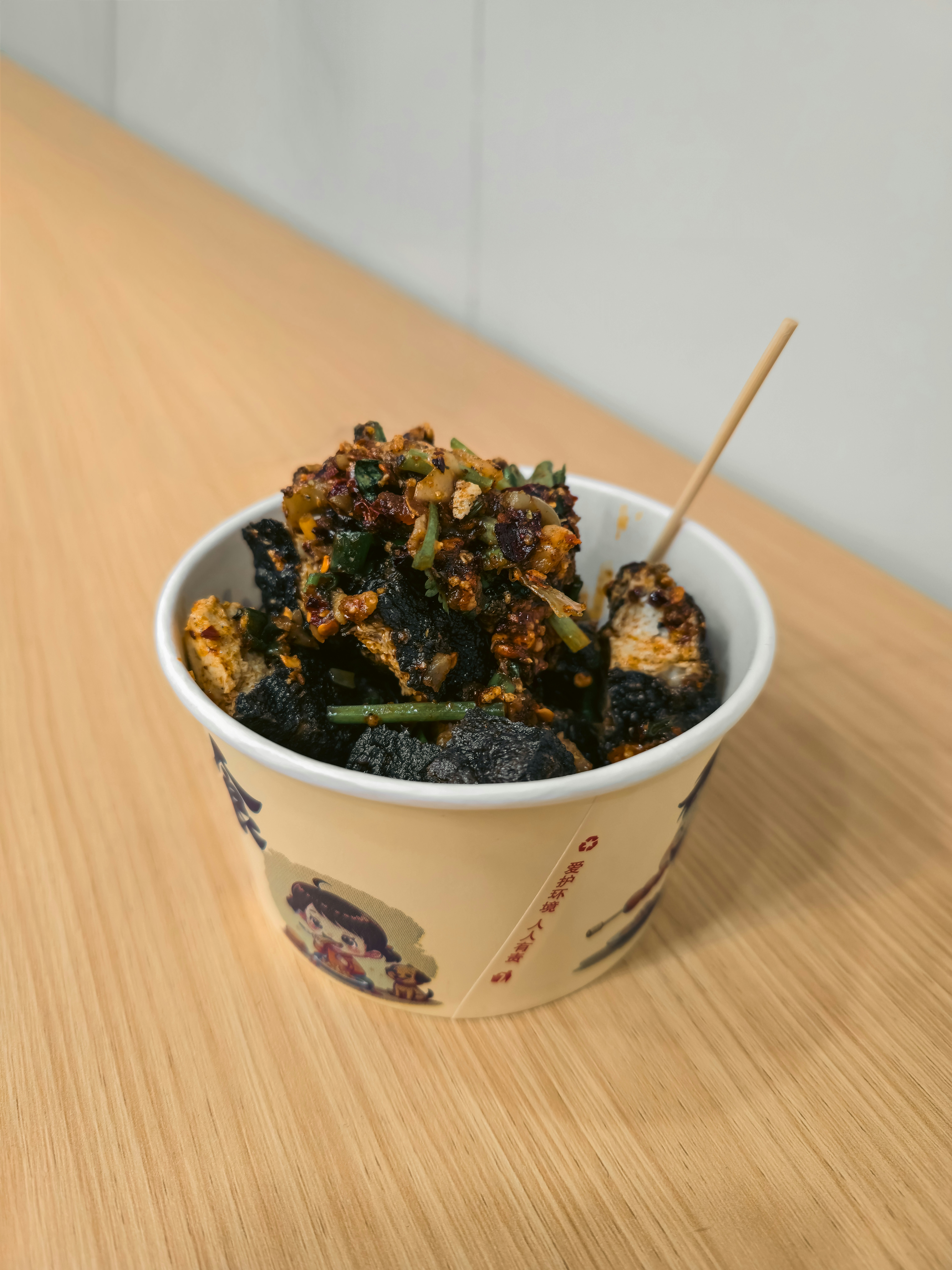 Changsha-stinkender Tofu, garniert mit Chilisauce und Kräutern in einem Pappbecher
