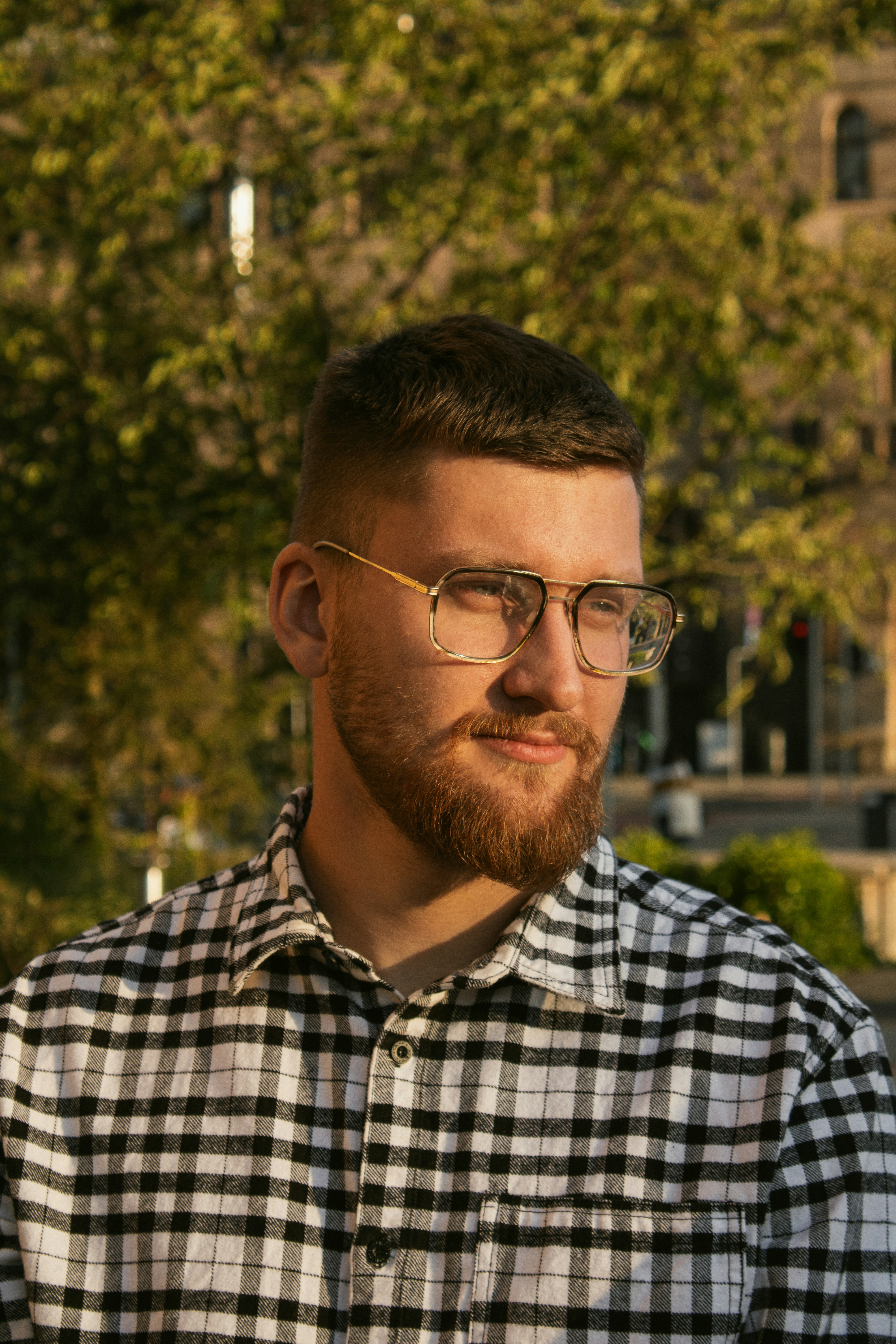 A man with a beard and glasses wearing a black and white checkered shirt