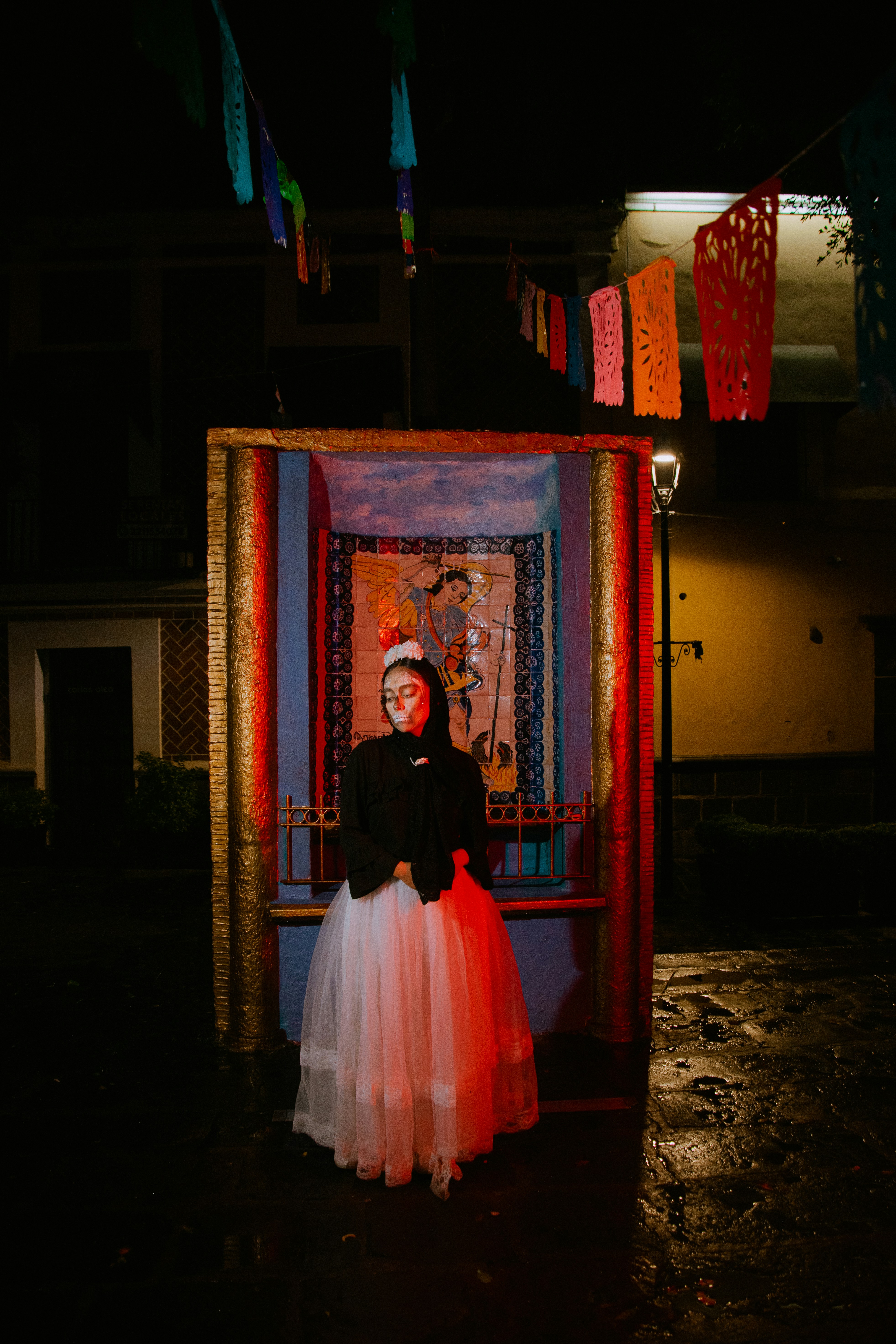 Fotomural A person with skull face paint in a white skirt before a tiled shrine