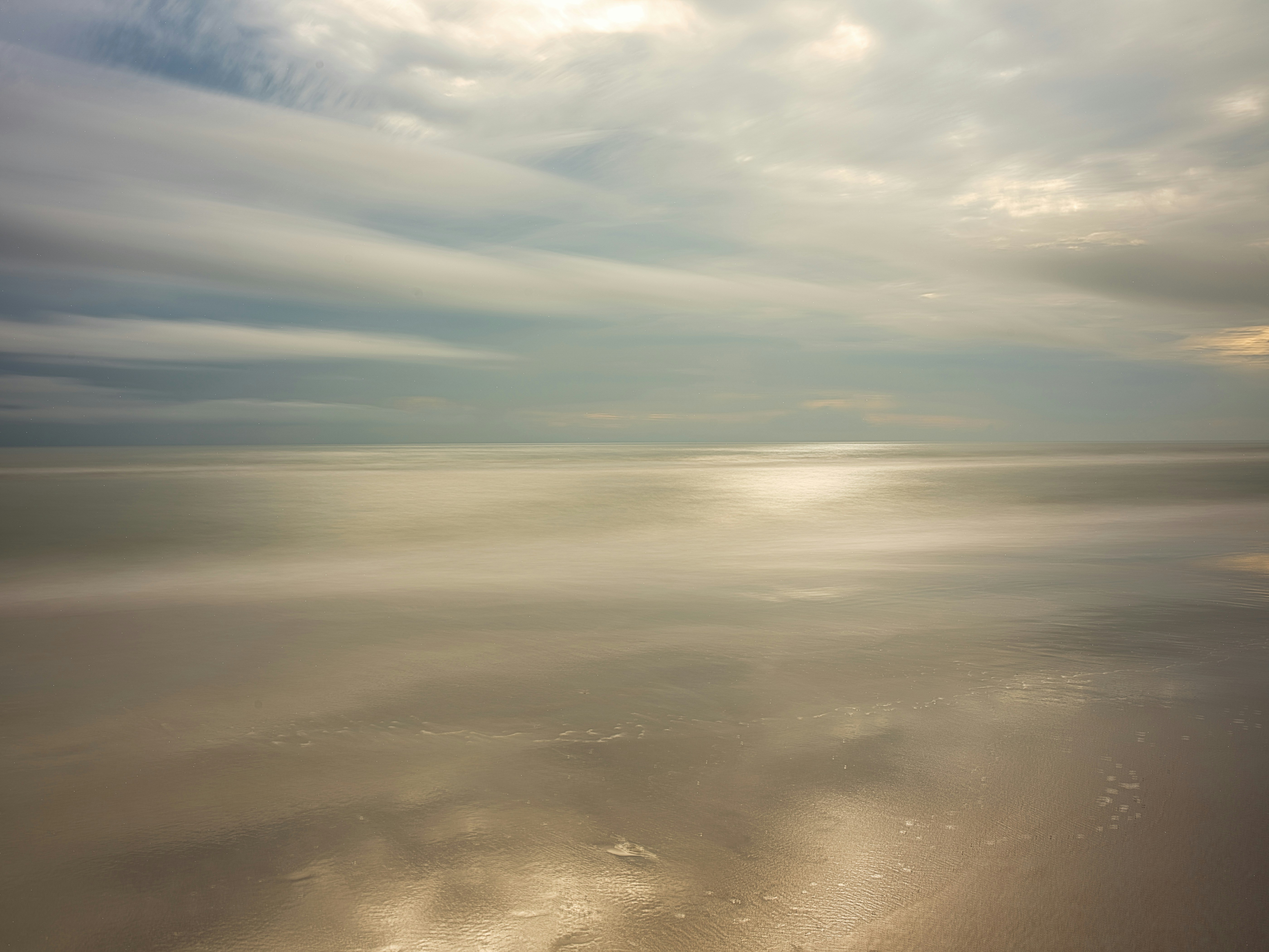 Larga exposición de un mar tranquilo bajo un cielo nublado con luz suave