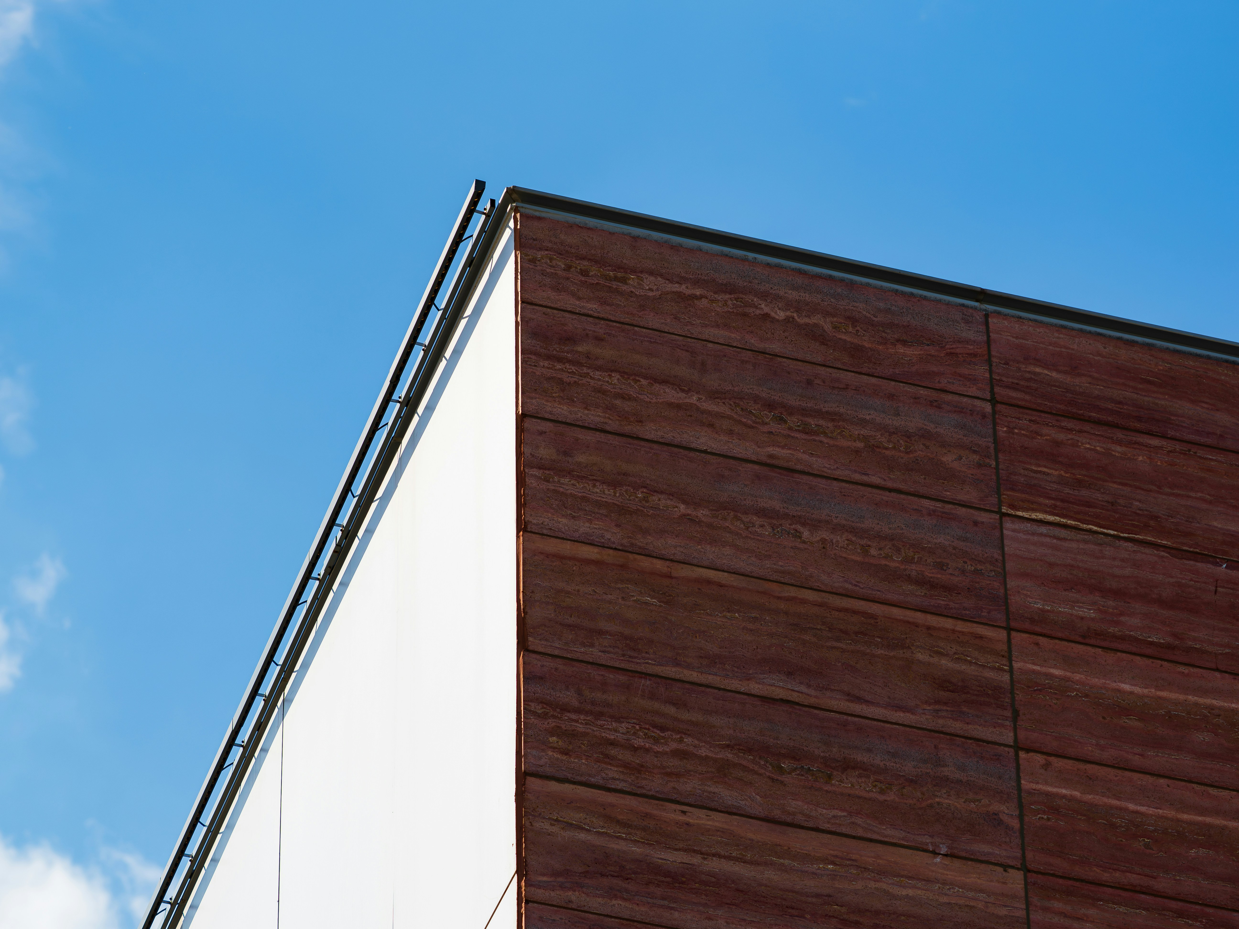 Un coin d’un bâtiment aux panneaux de pierre blanches et rouges sur un ciel bleu