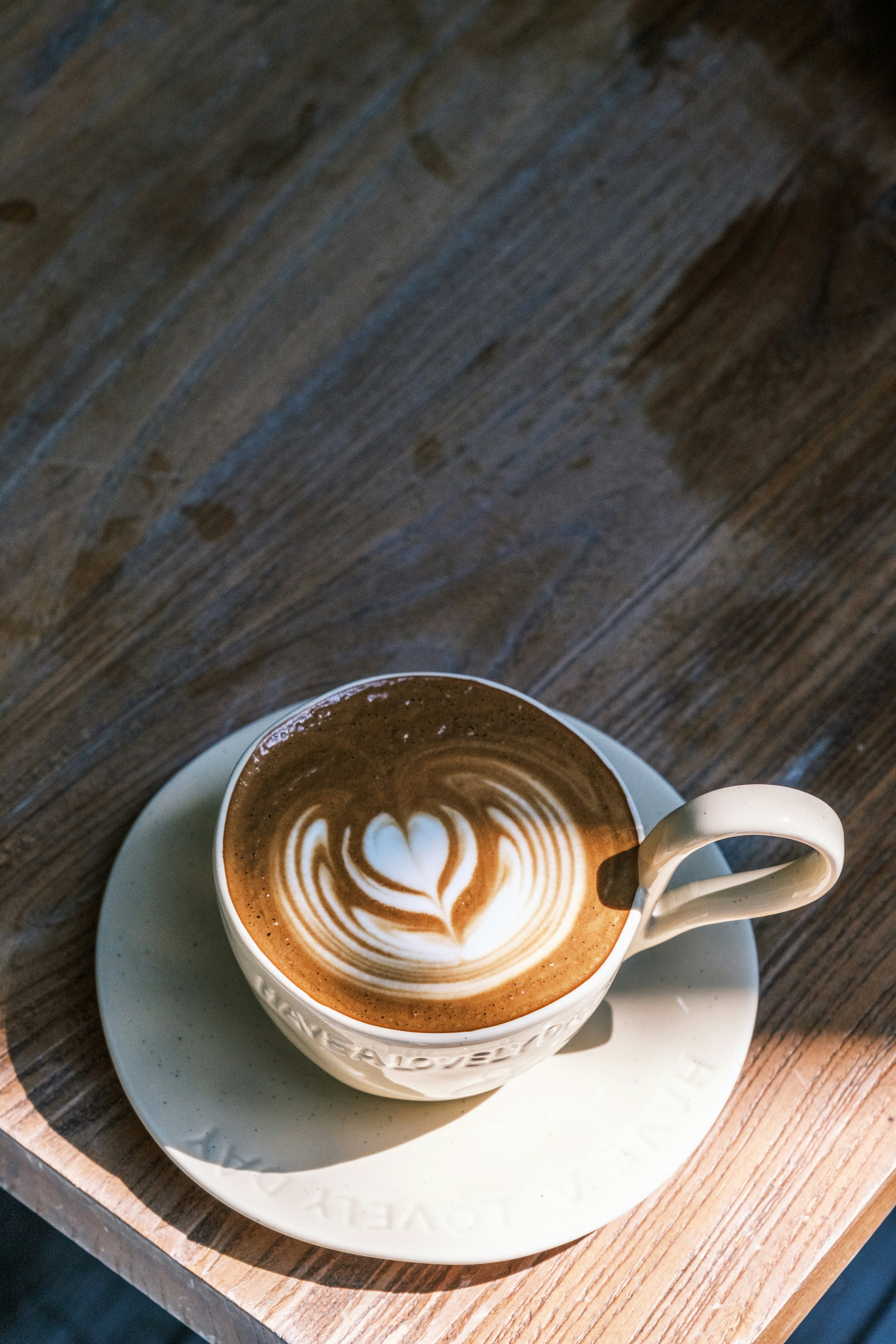 A cup of latte with heart latte art on a wooden table
