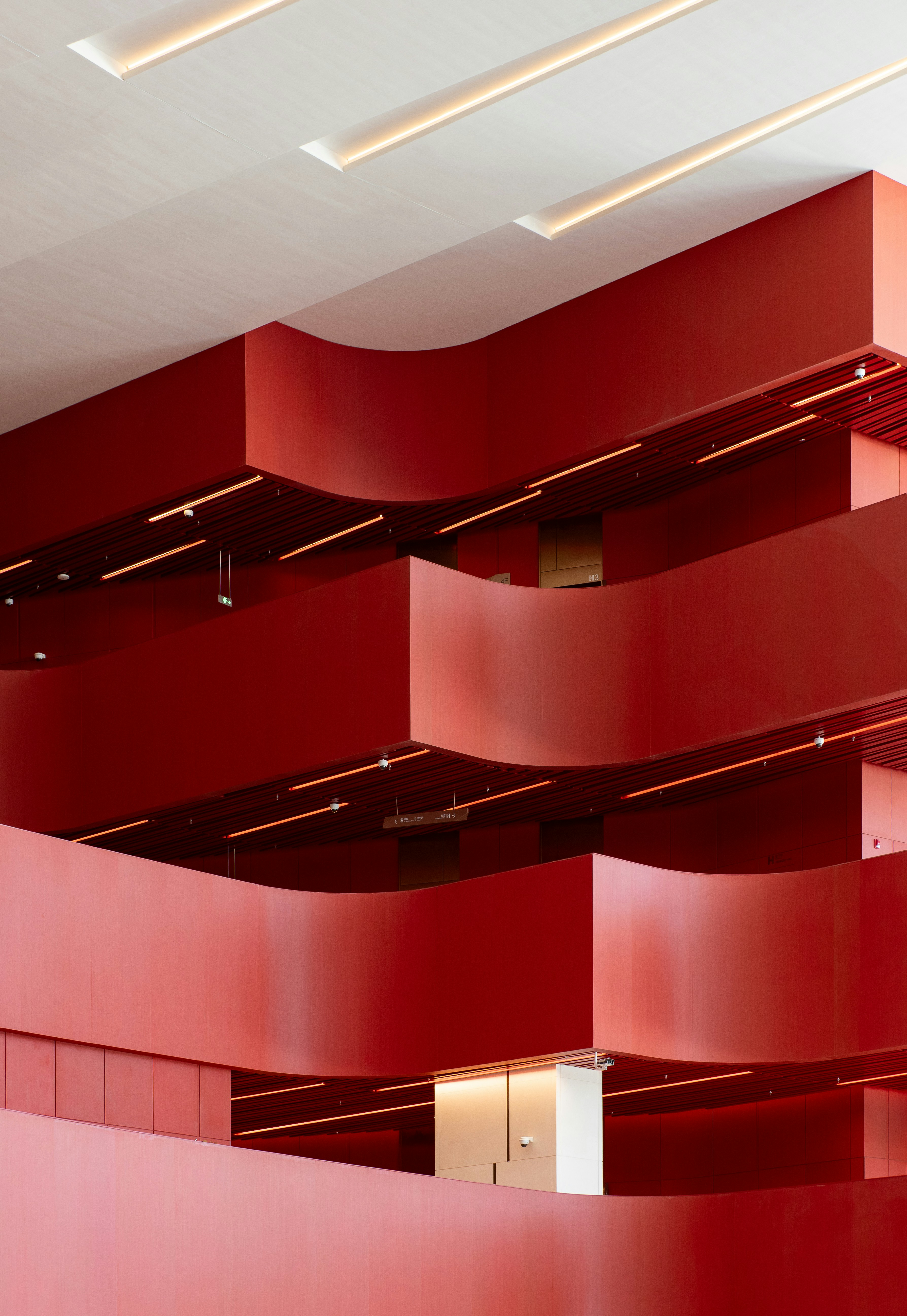 Curved red balconies in a modern building interior with recessed ceiling lighting