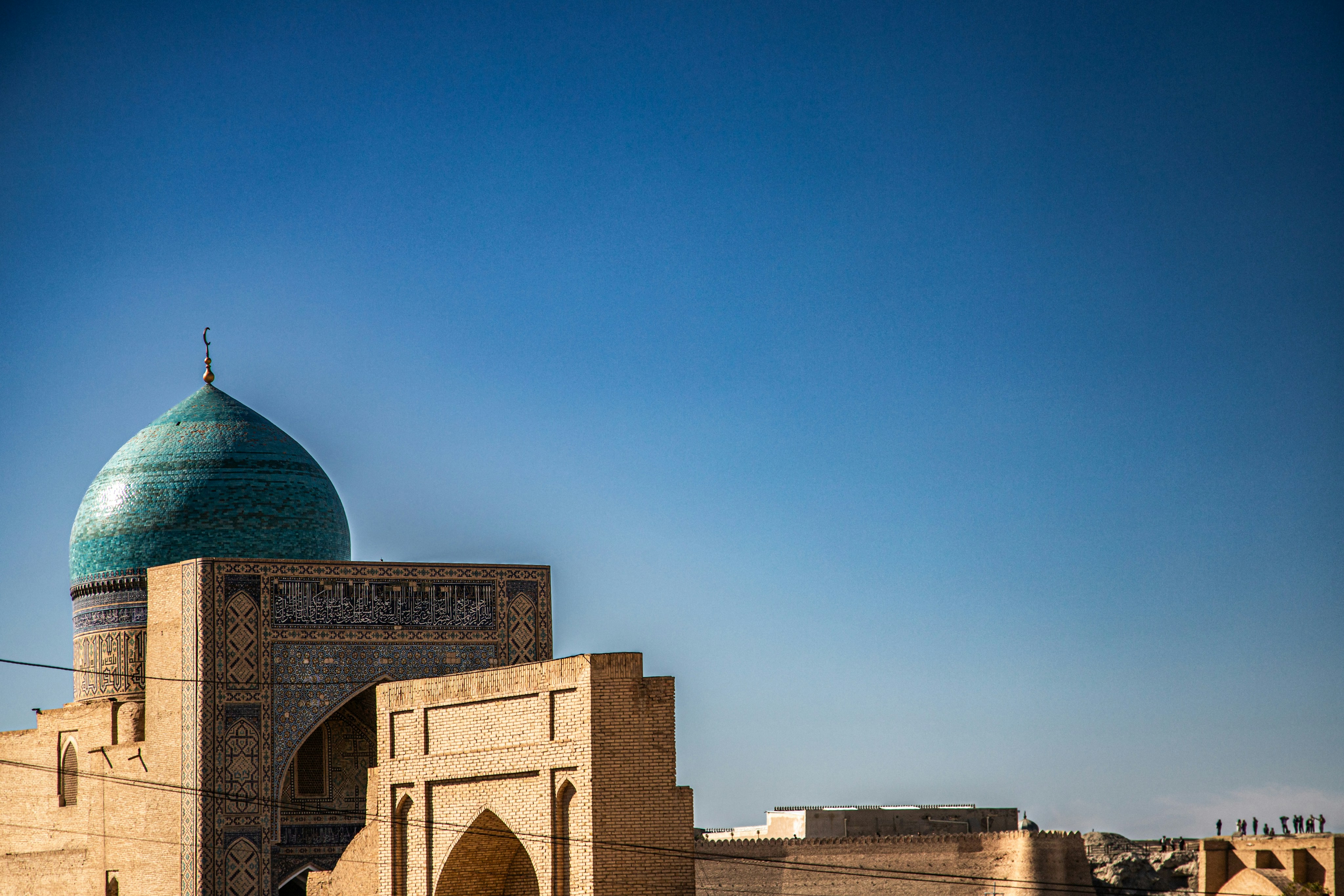 A turquoise dome atop a brick building with intricate tilework under a clear sky