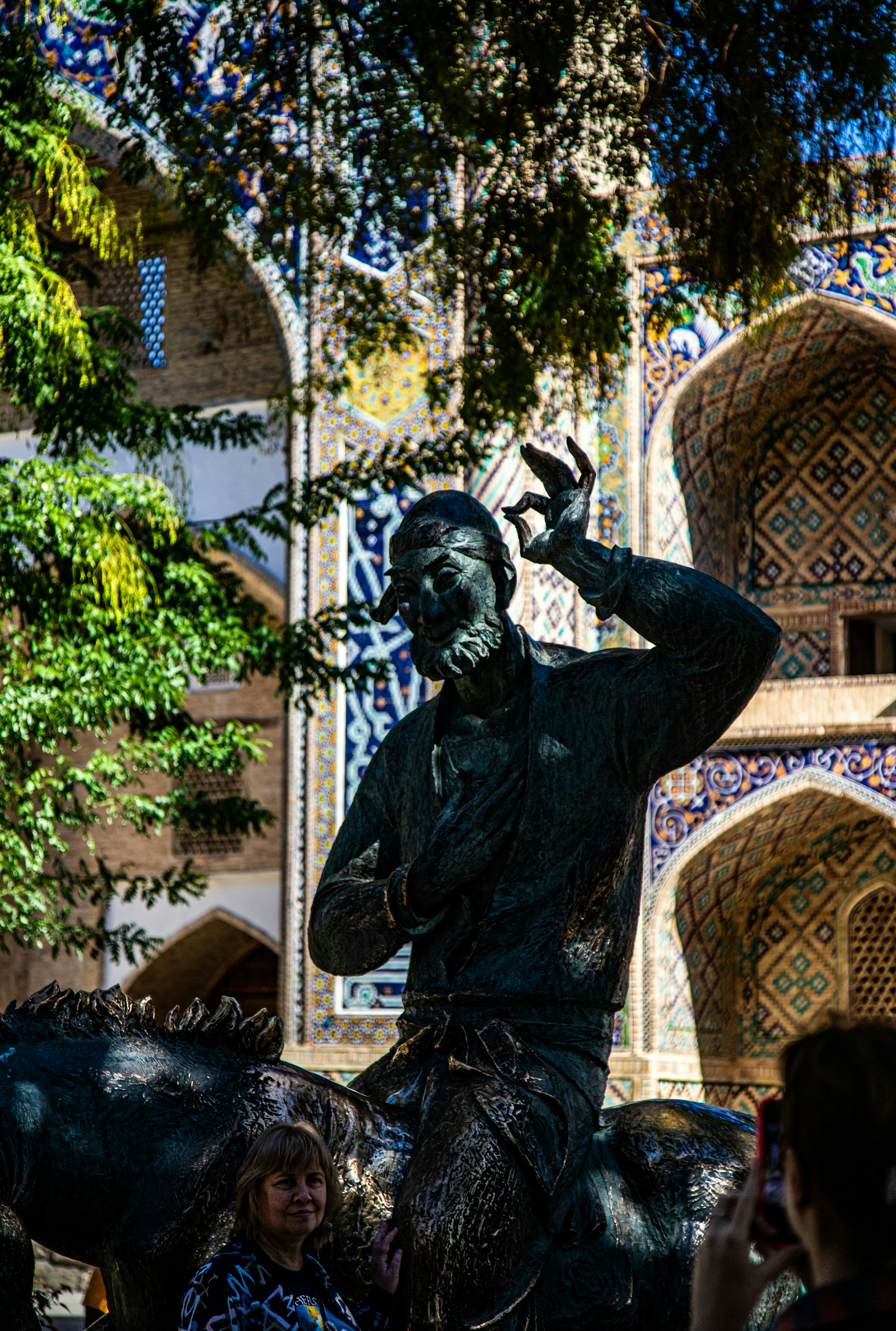 A bronze statue of a man on a horse before a tiled archway