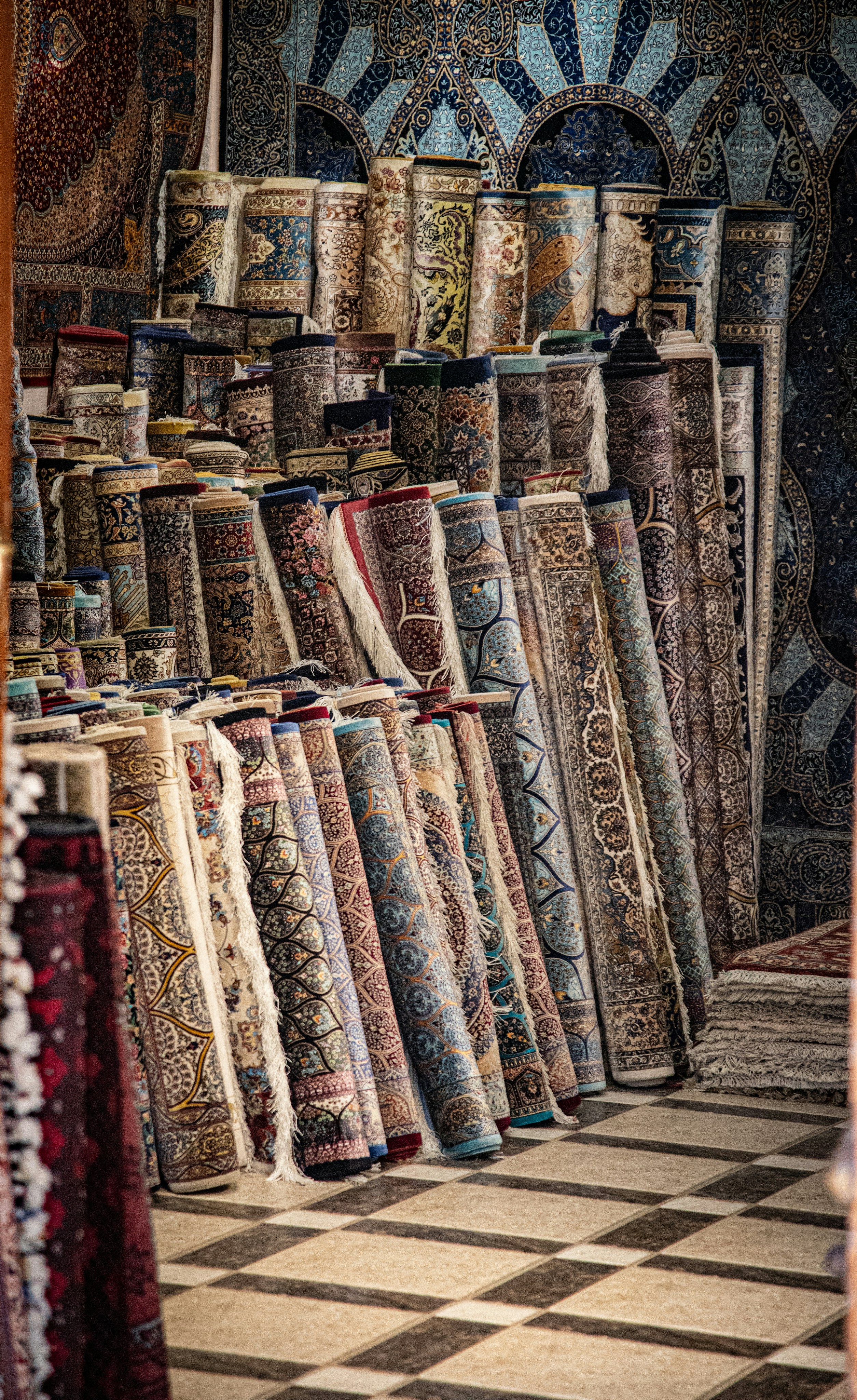 Many rolled Persian rugs with intricate patterns stacked in a shop