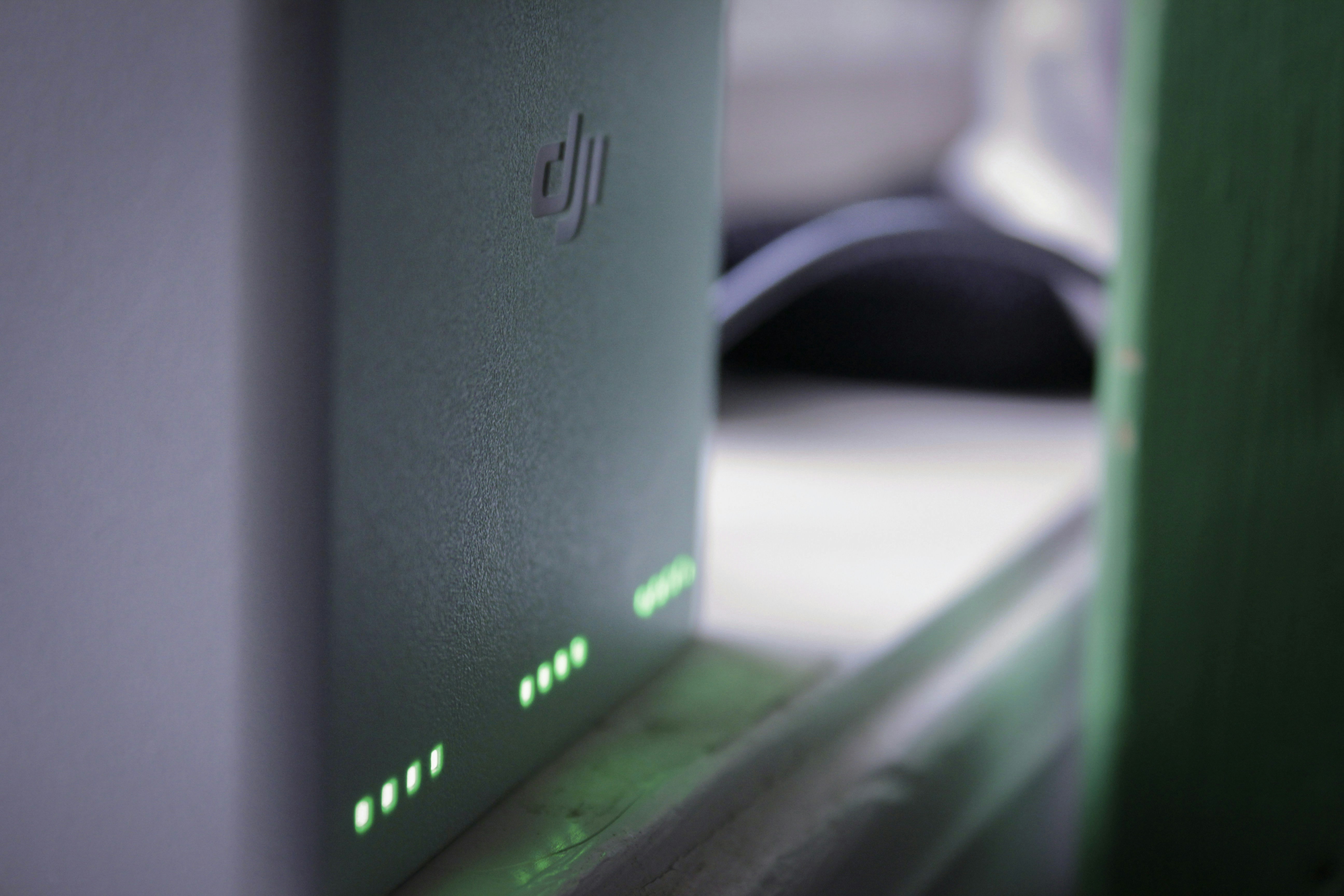 A DJI device with glowing green status lights on a white surface