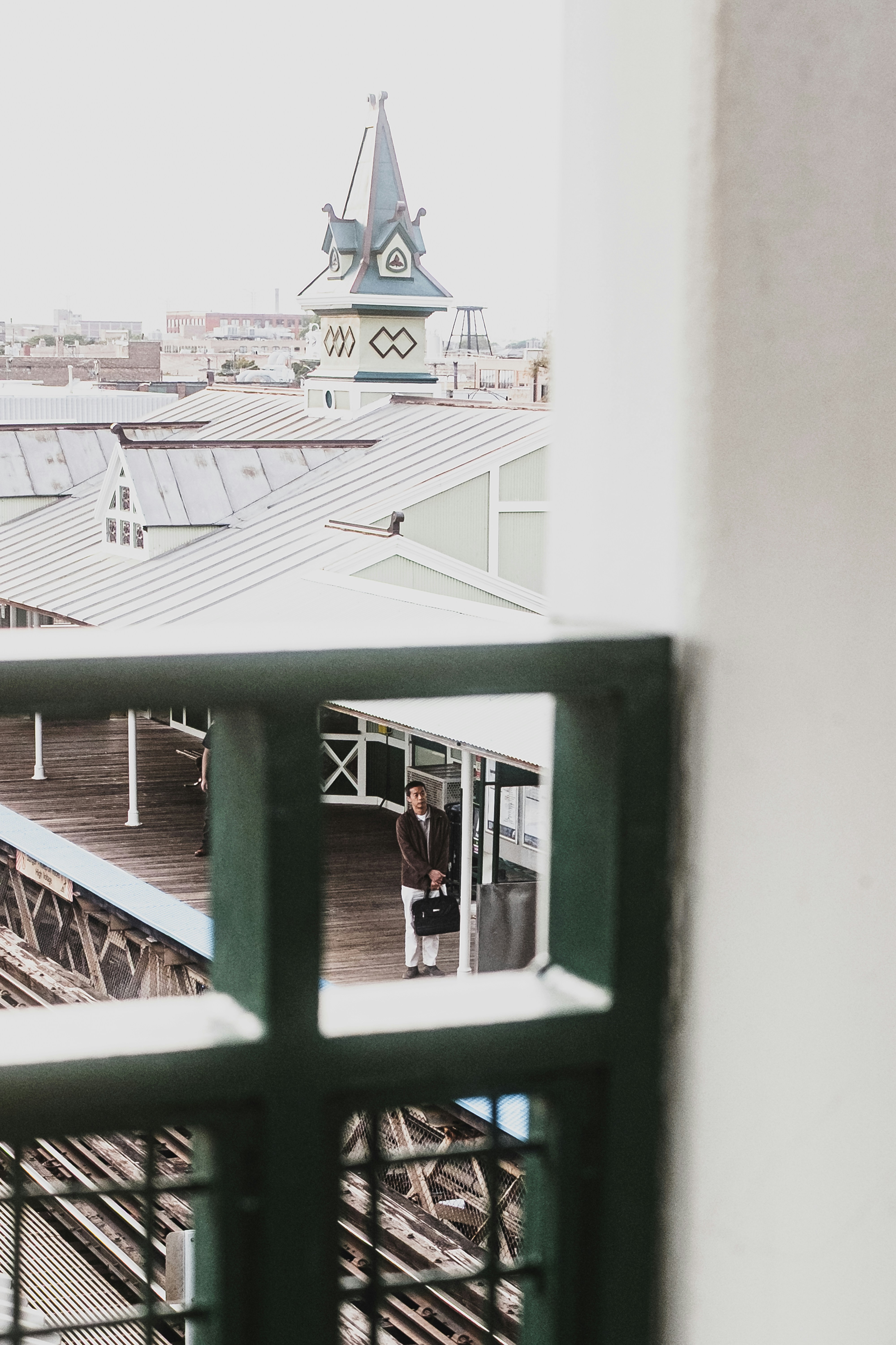 A person with a briefcase on a wooden train platform near a clock tower