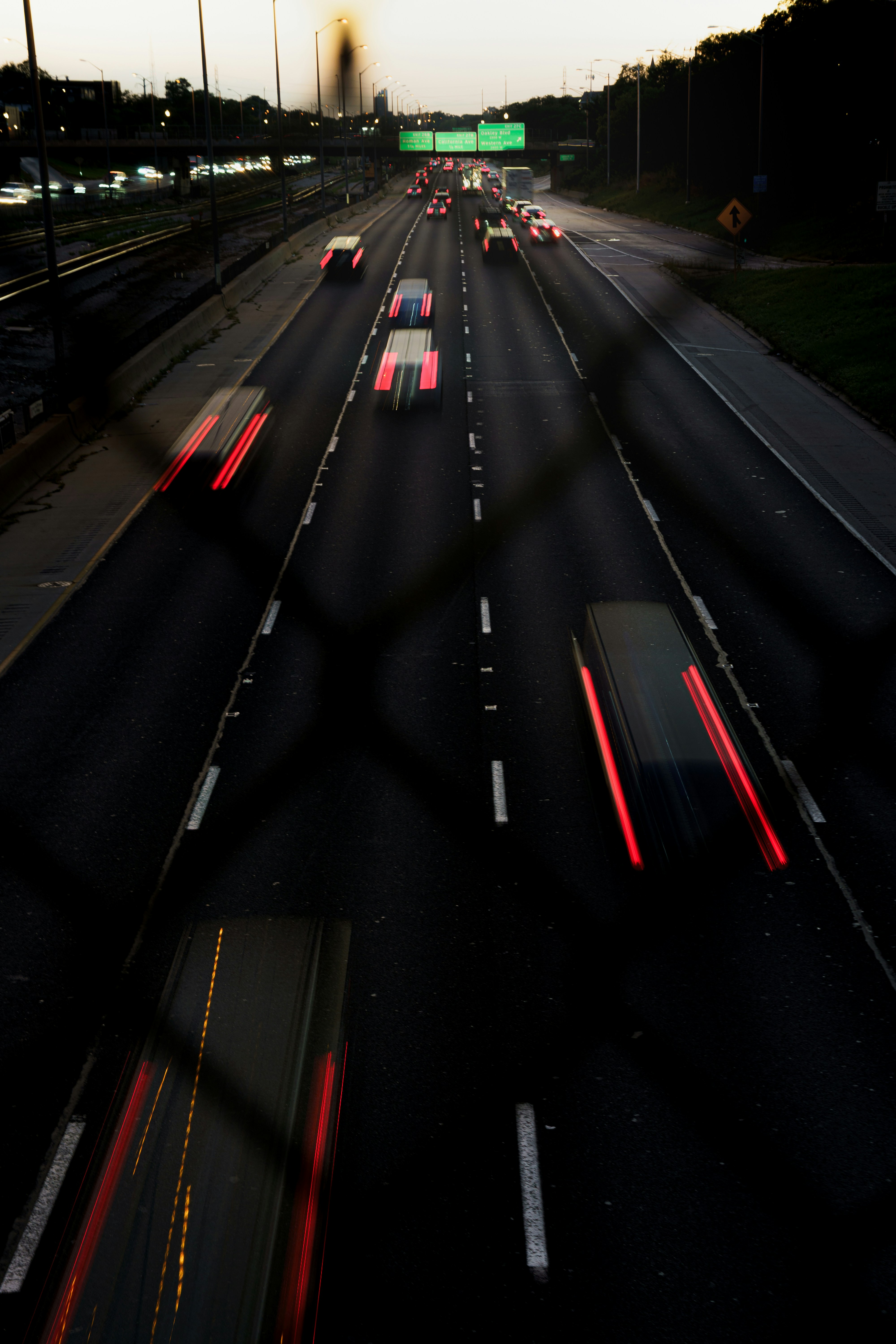 Long exposure of car taillights on a highway at night behind a fence