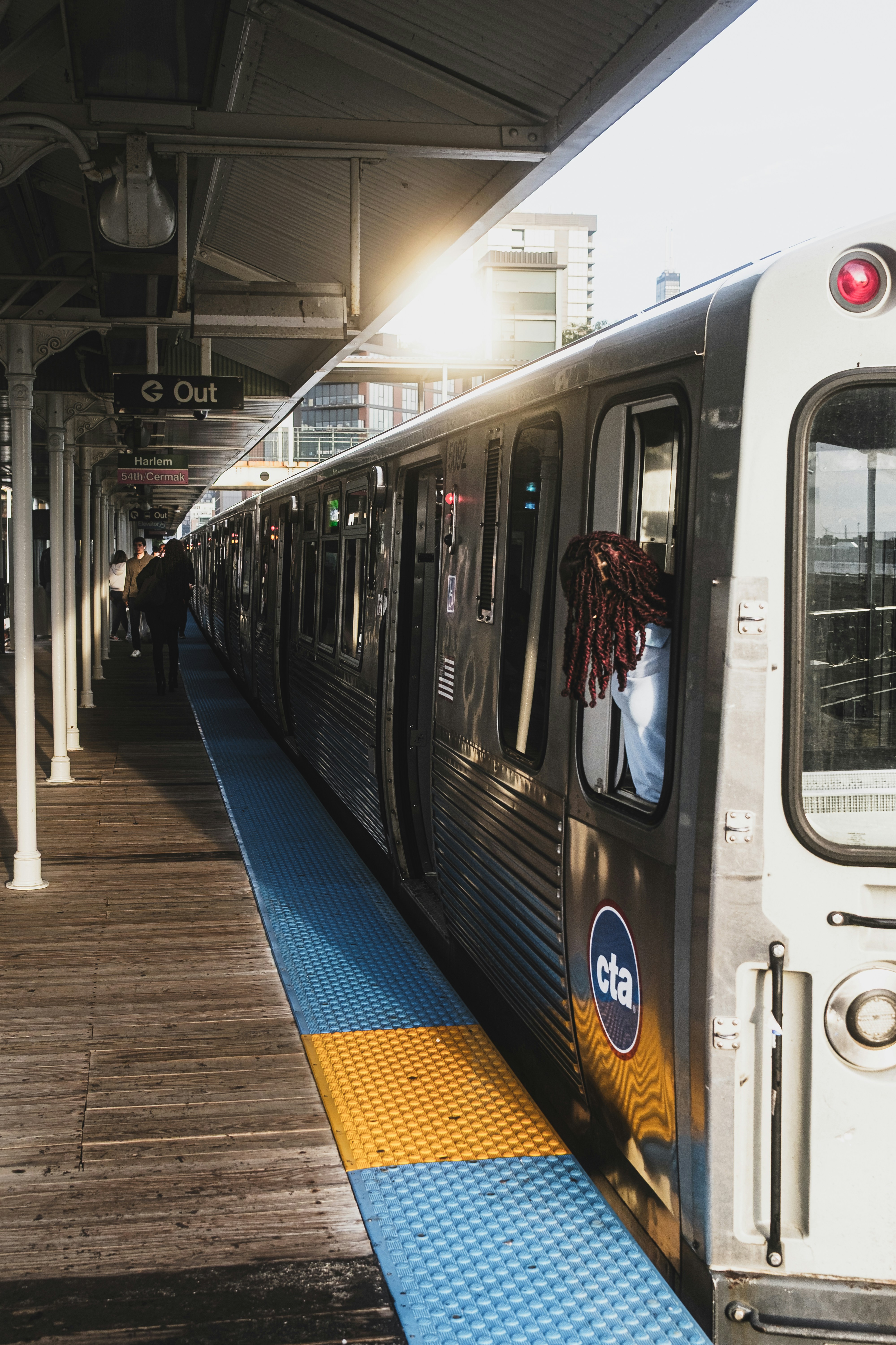 A person leaning out of a CTA train window at a station platform
