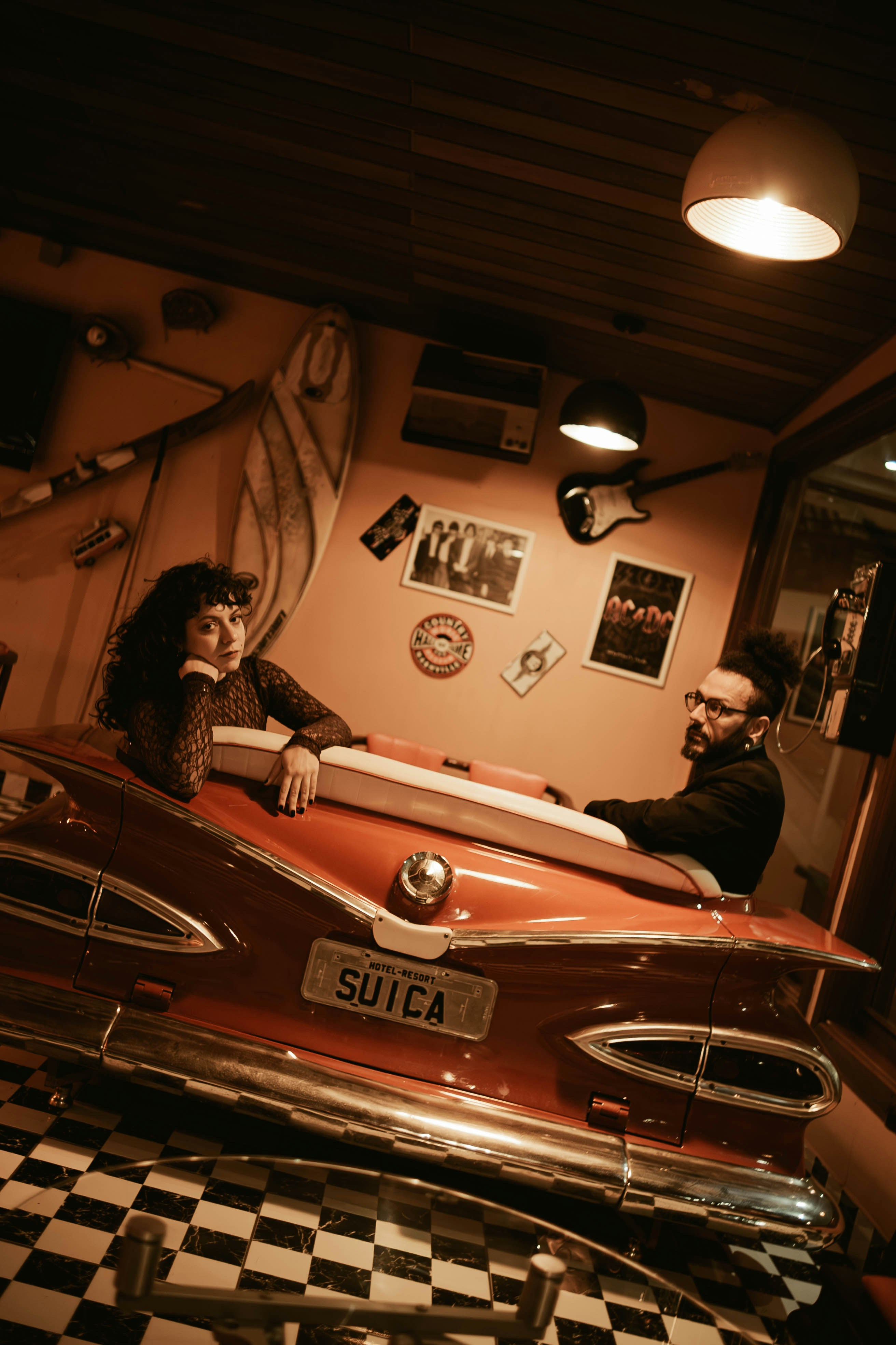Two people sitting in a red vintage car booth inside a retro diner