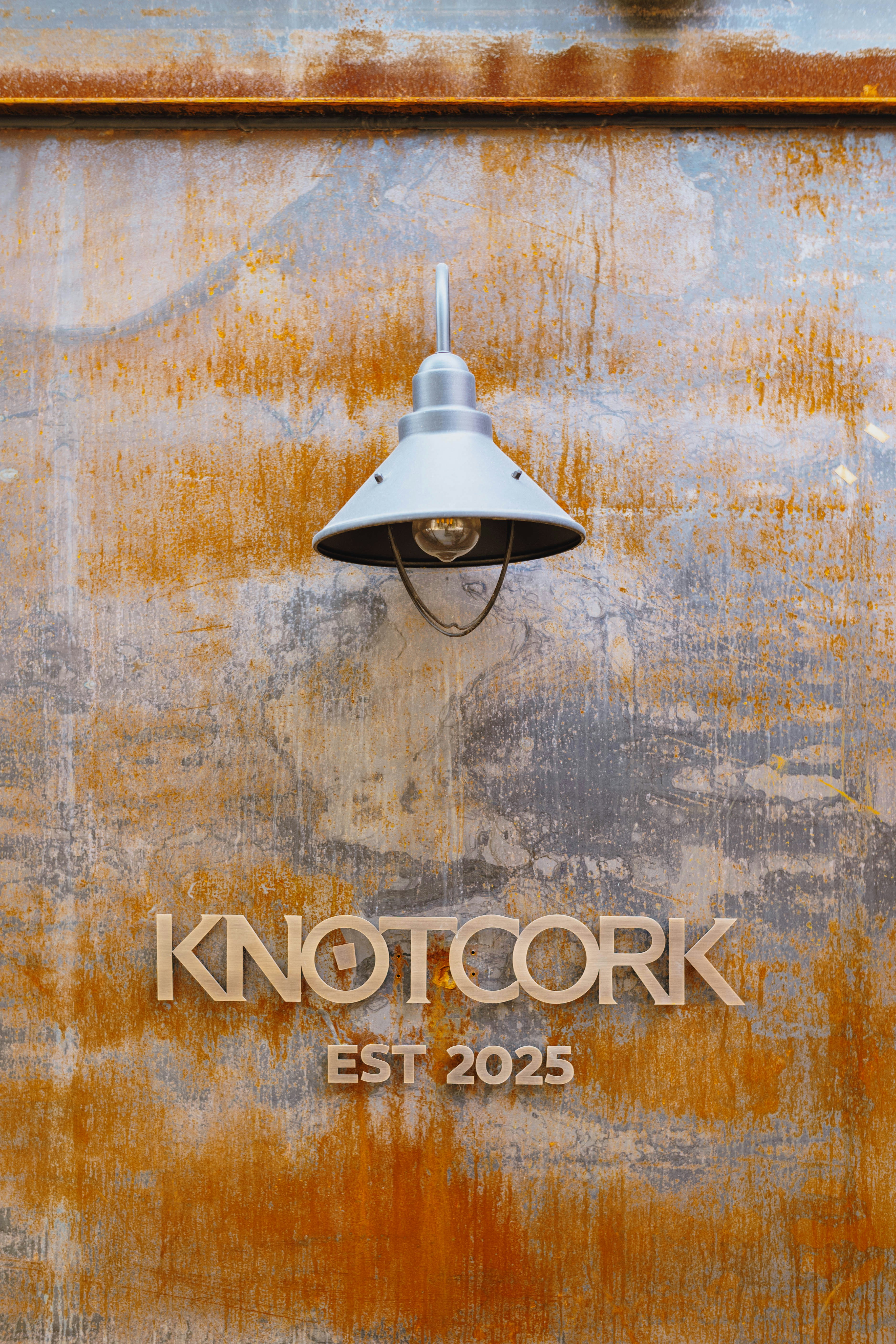 錆びた壁の上の看板の上の金属製ランプ KNOTCORK EST 2025
