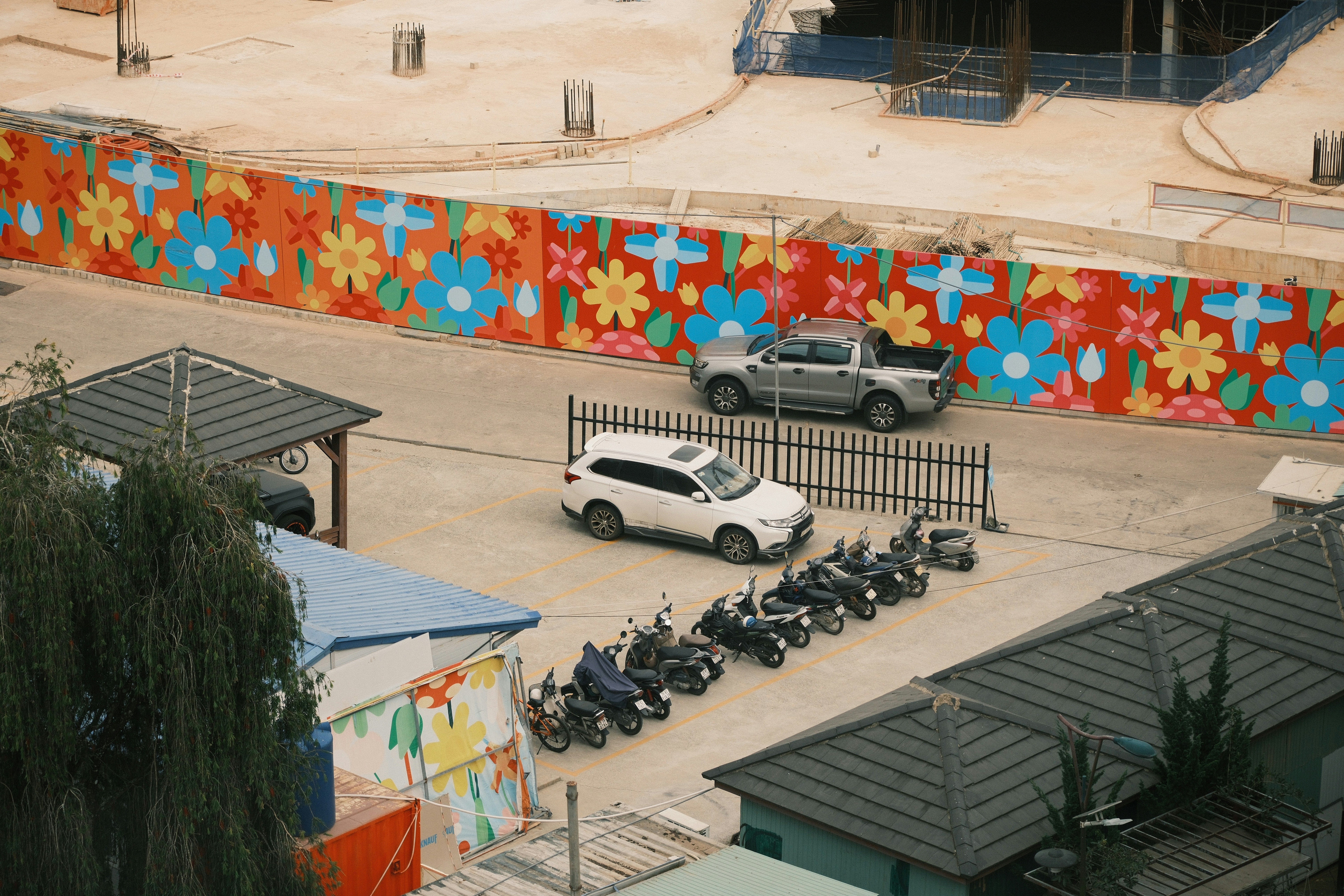 An aerial view of a parking lot with a colorful floral mural on a wall