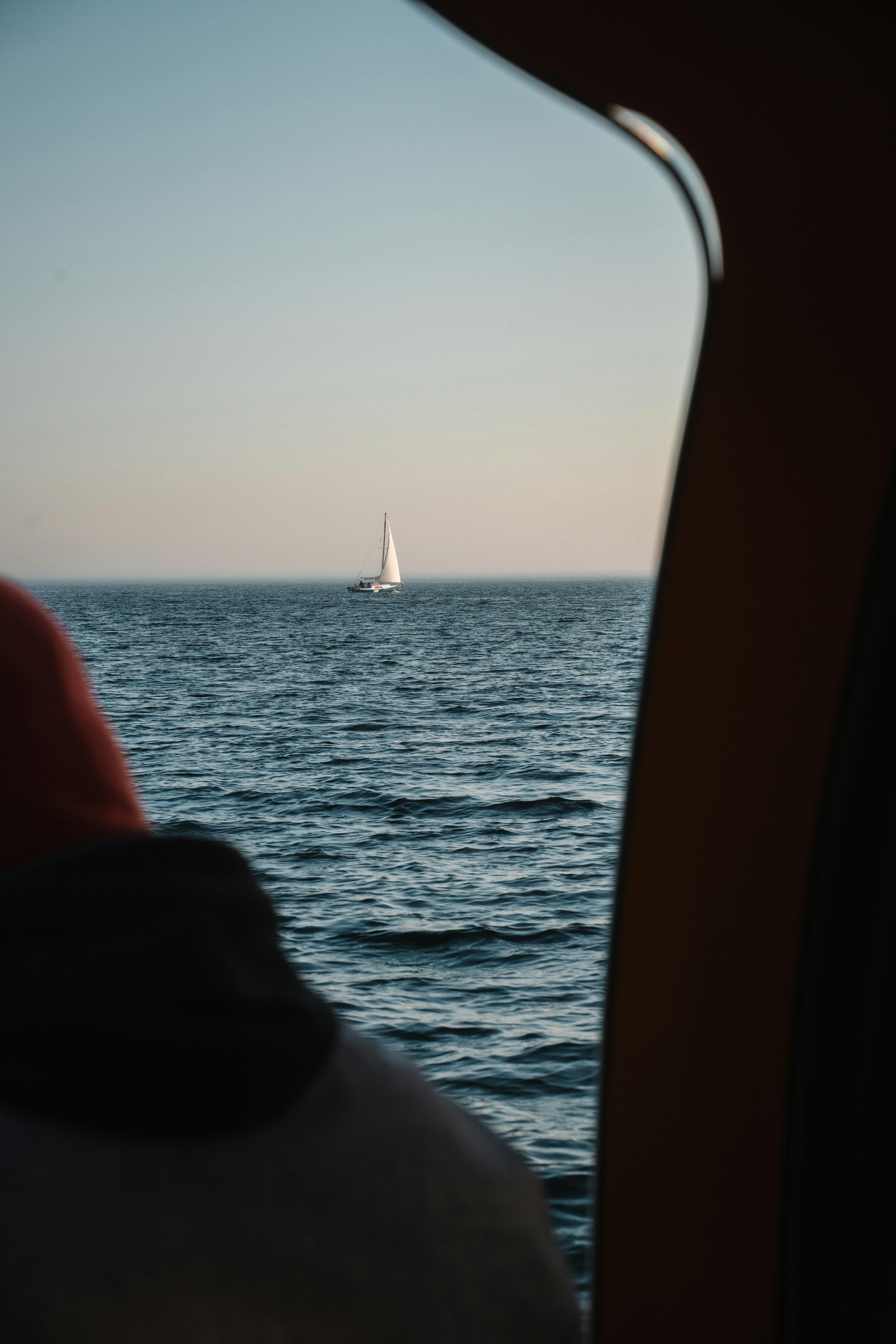 A sailboat on the open sea viewed through a window frame