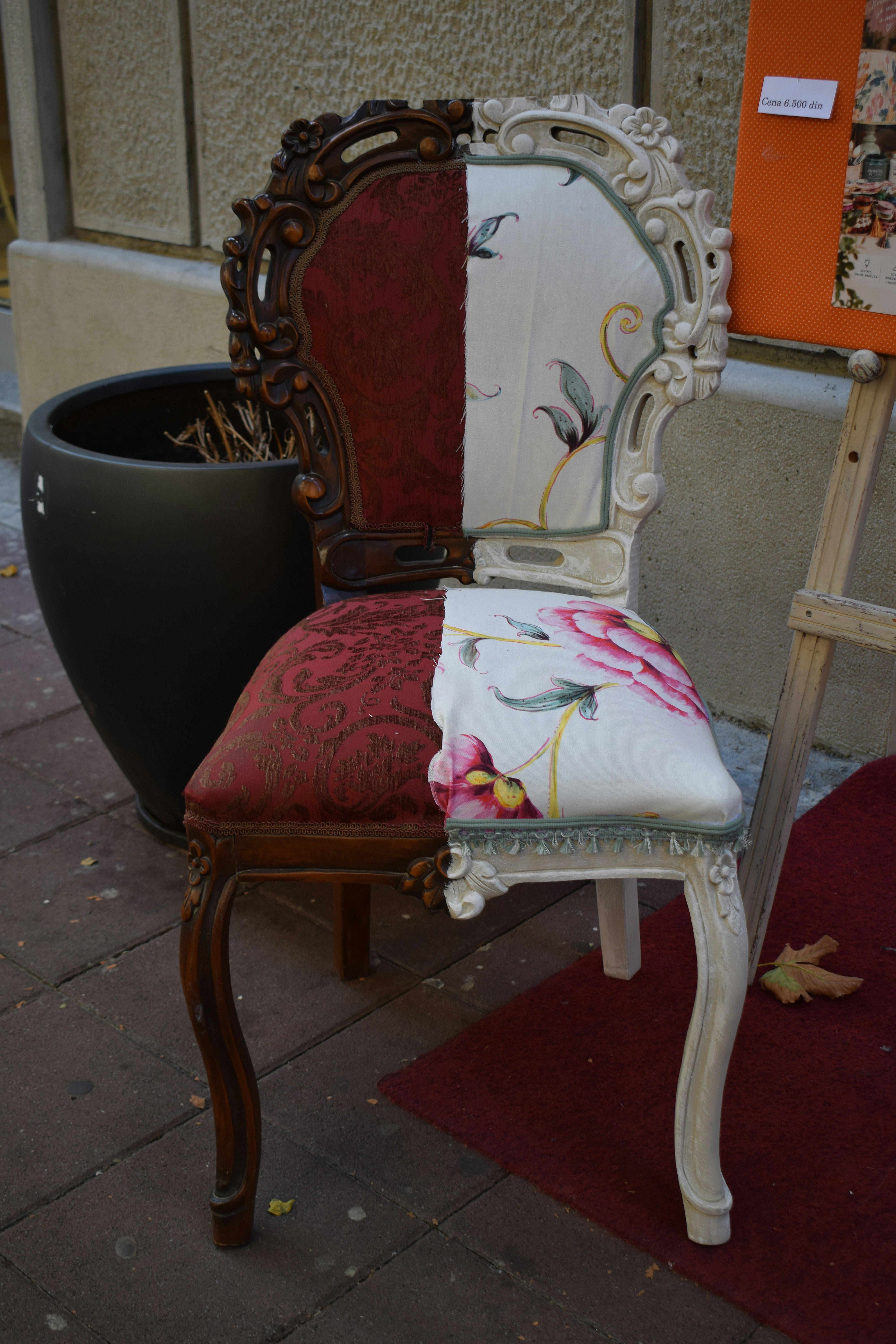 A chair split between dark wood with red fabric and white wood with floral fabric
