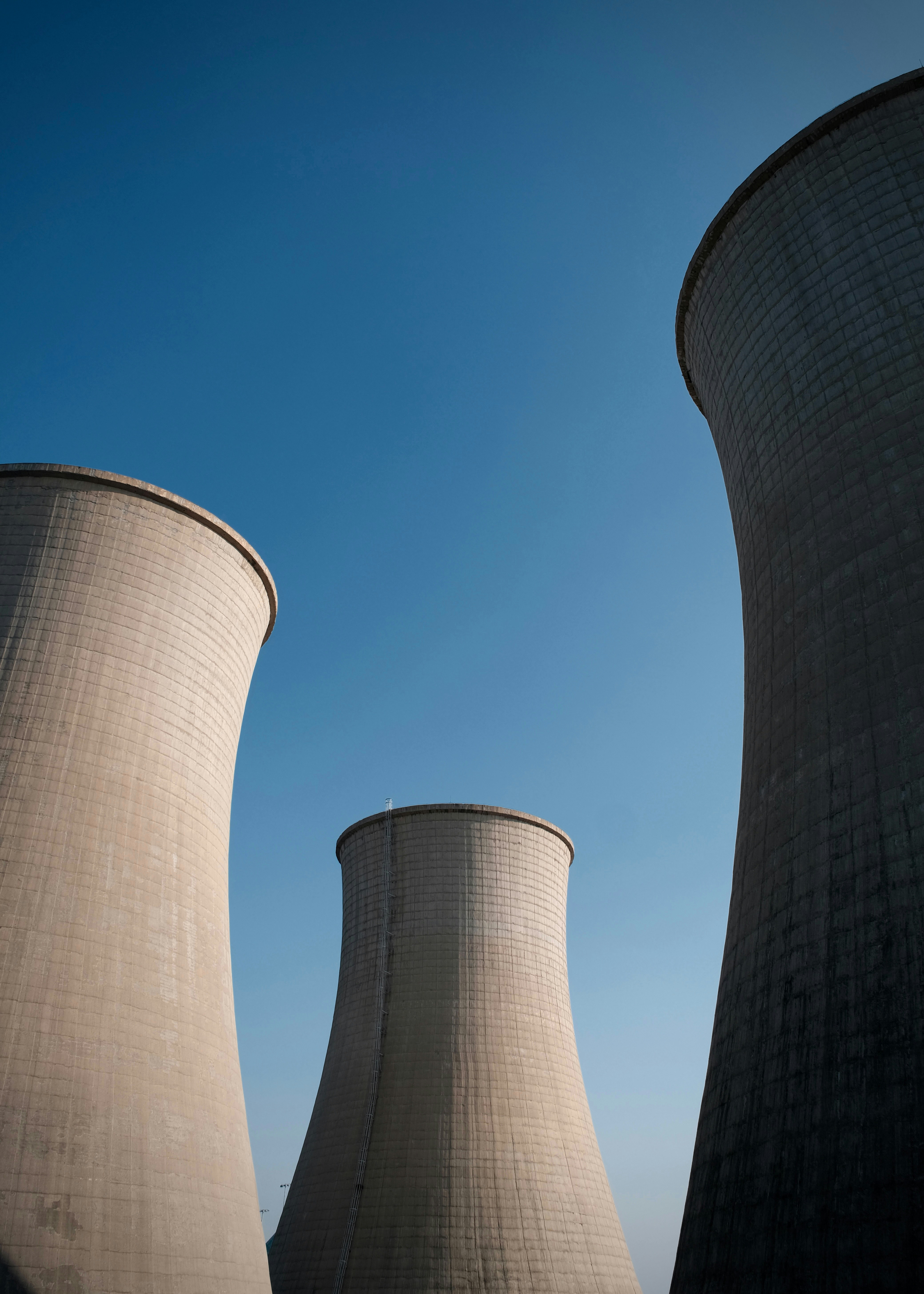 Three large concrete cooling towers against a clear blue sky