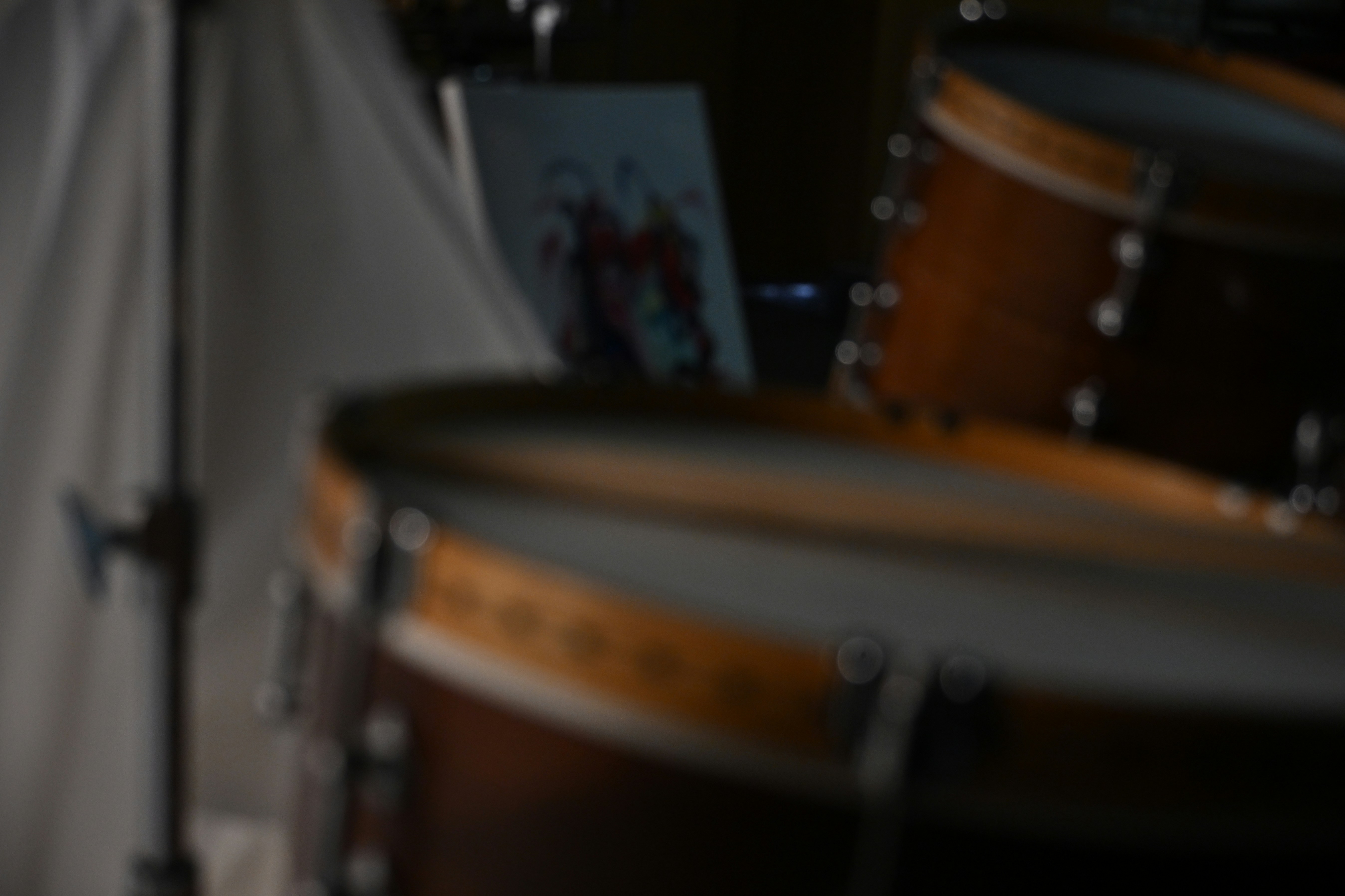 A close-up of a wooden drum kit in a dimly lit room