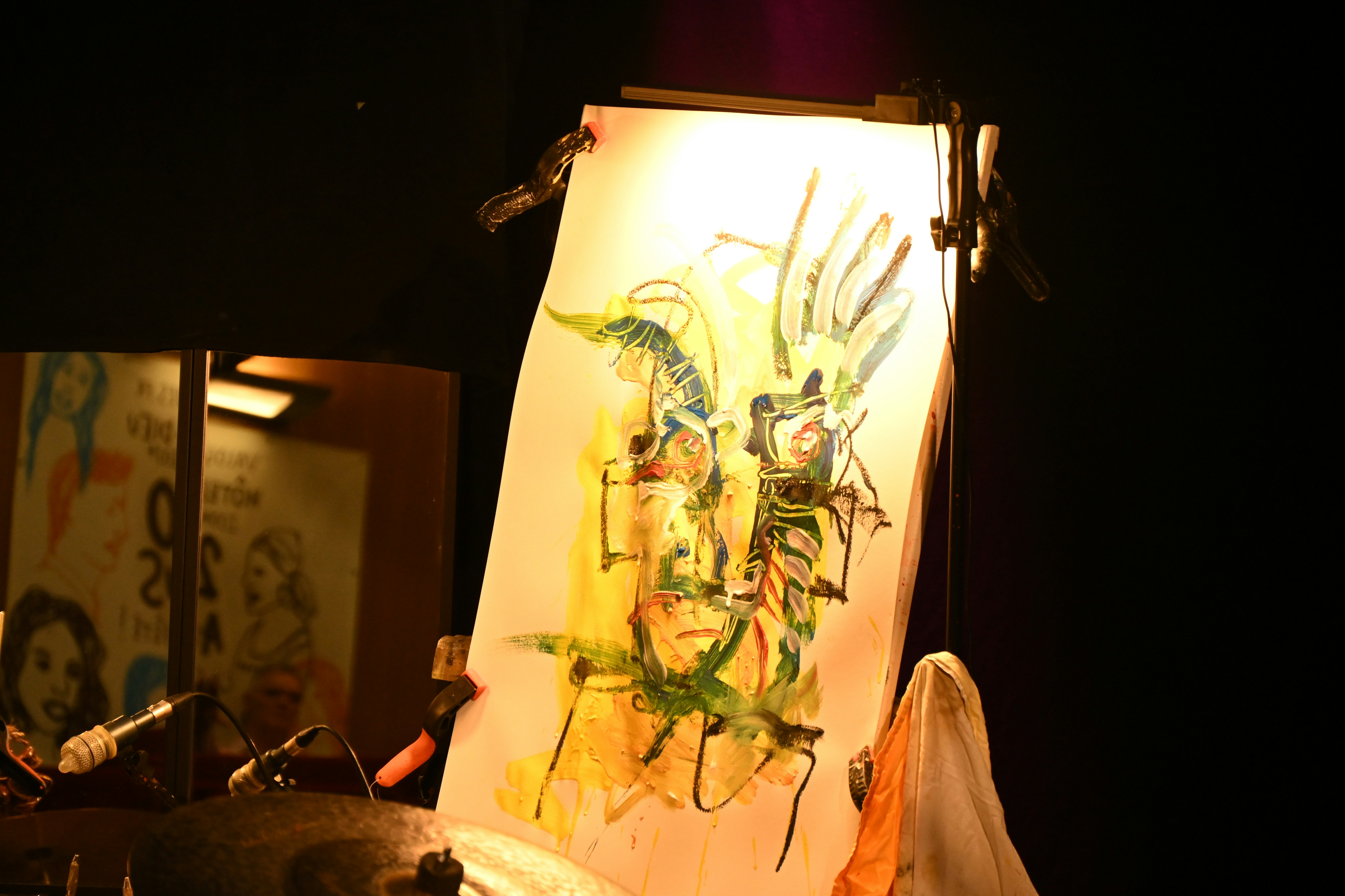A painting of an abstract face on a white canvas illuminated by a bright spotlight