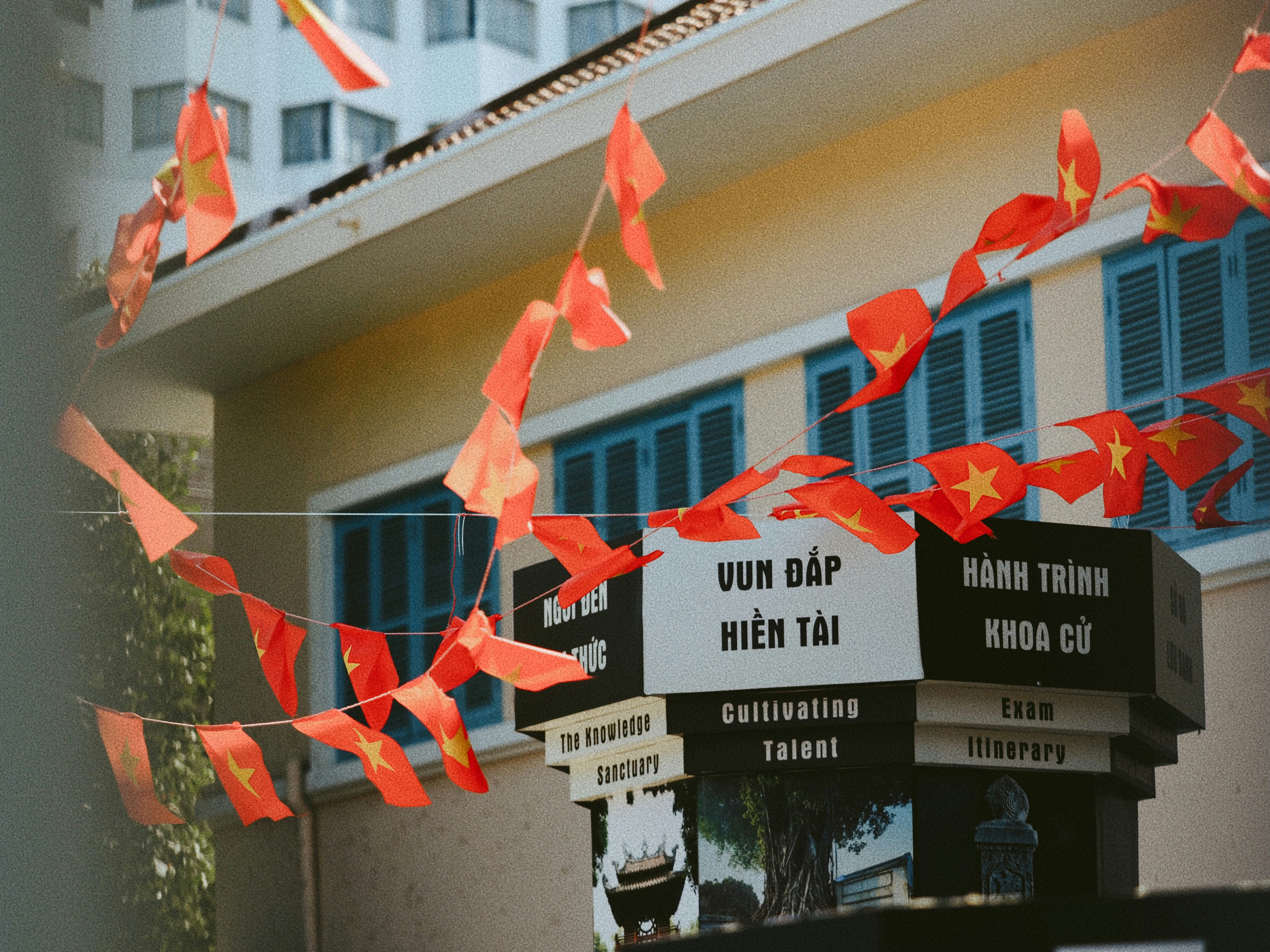 Red flags with yellow stars hanging above a sign with Vietnamese text