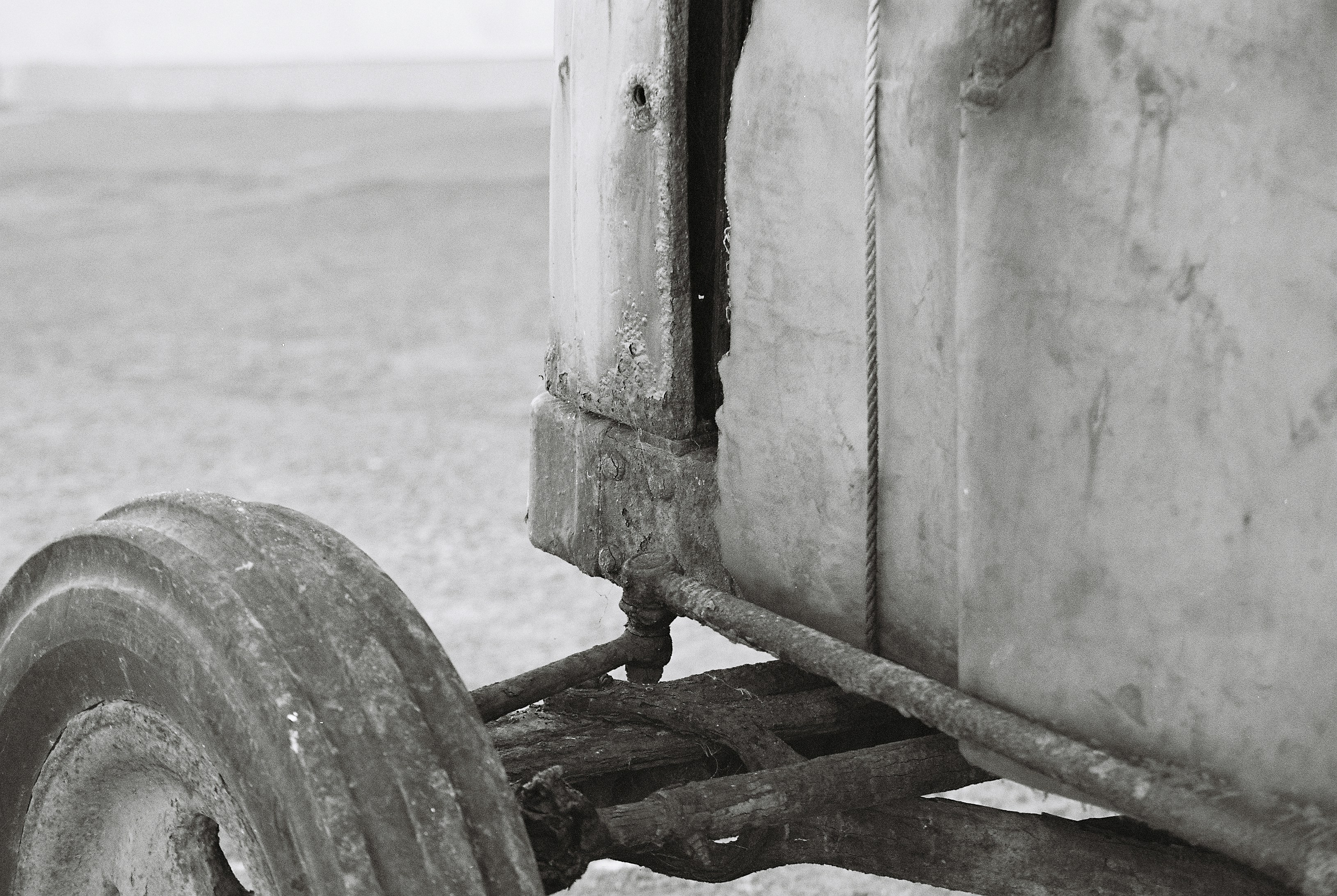 A weathered machine panel with flaking paint and a hanging rope above rusty beams
