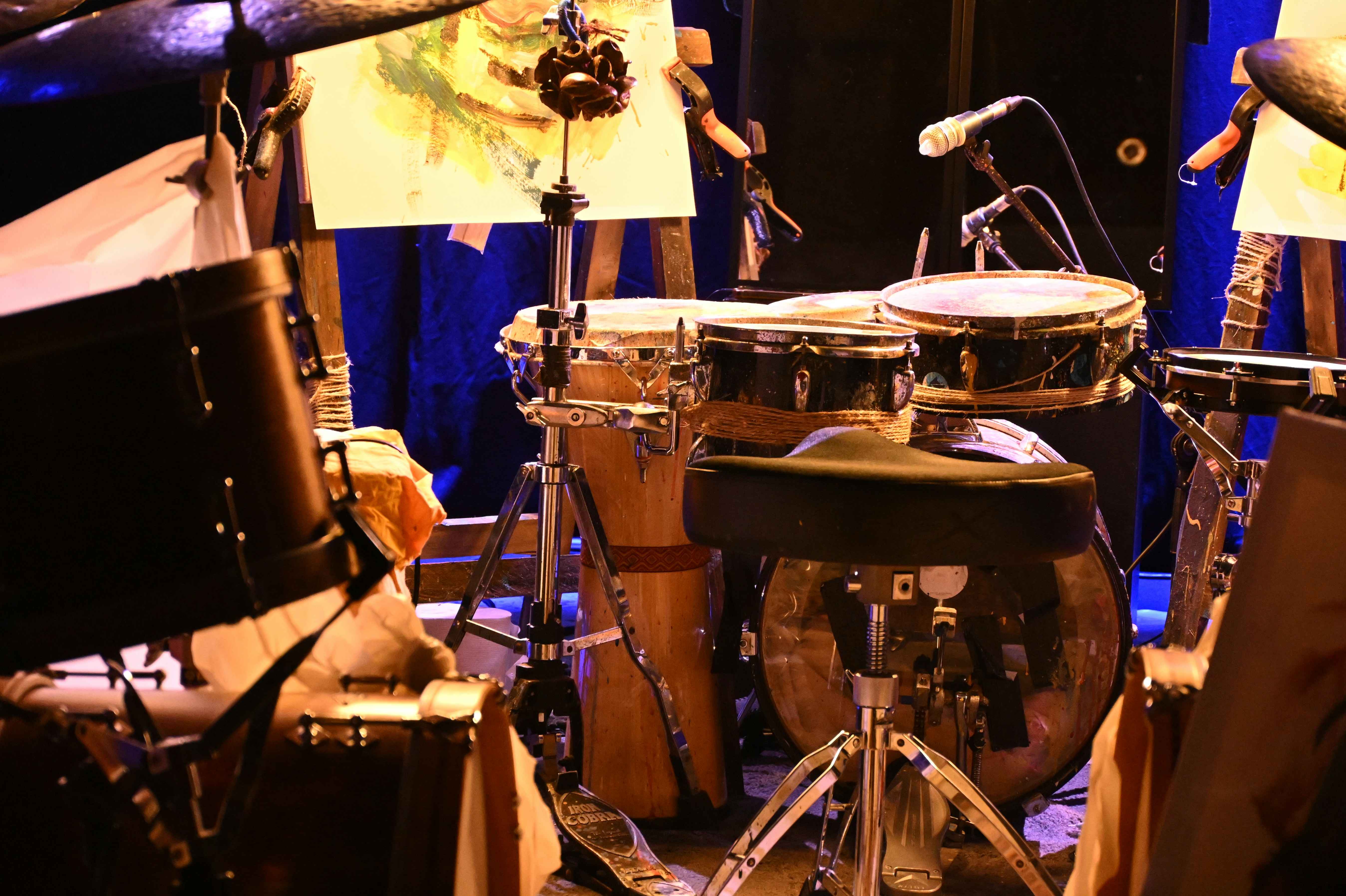 A drum kit with congas and a bass drum on a stage with art easels