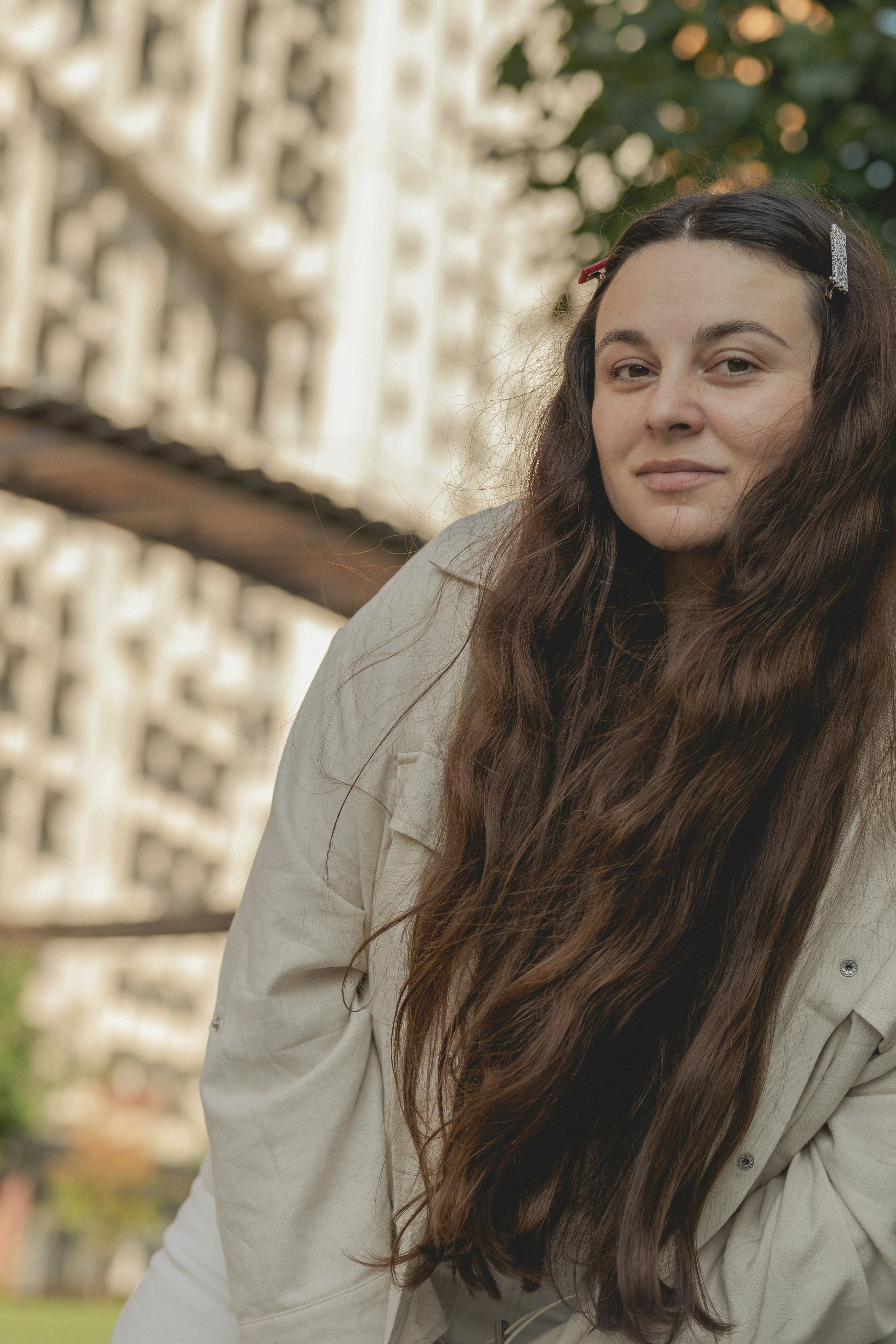 Una mujer con el pelo largo y castaño y pasadores en una chaqueta beige