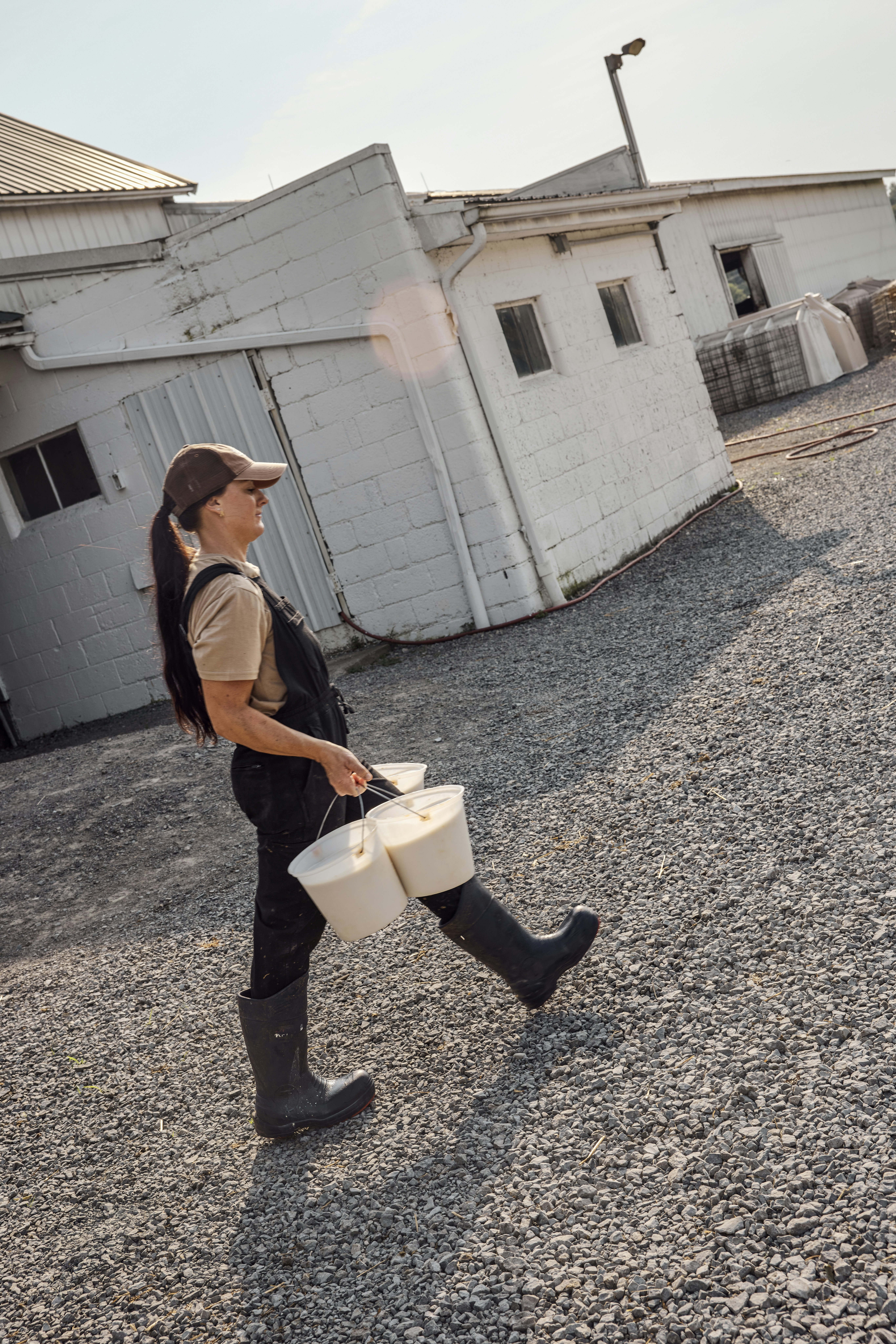 Woman carrying buckets across a farm