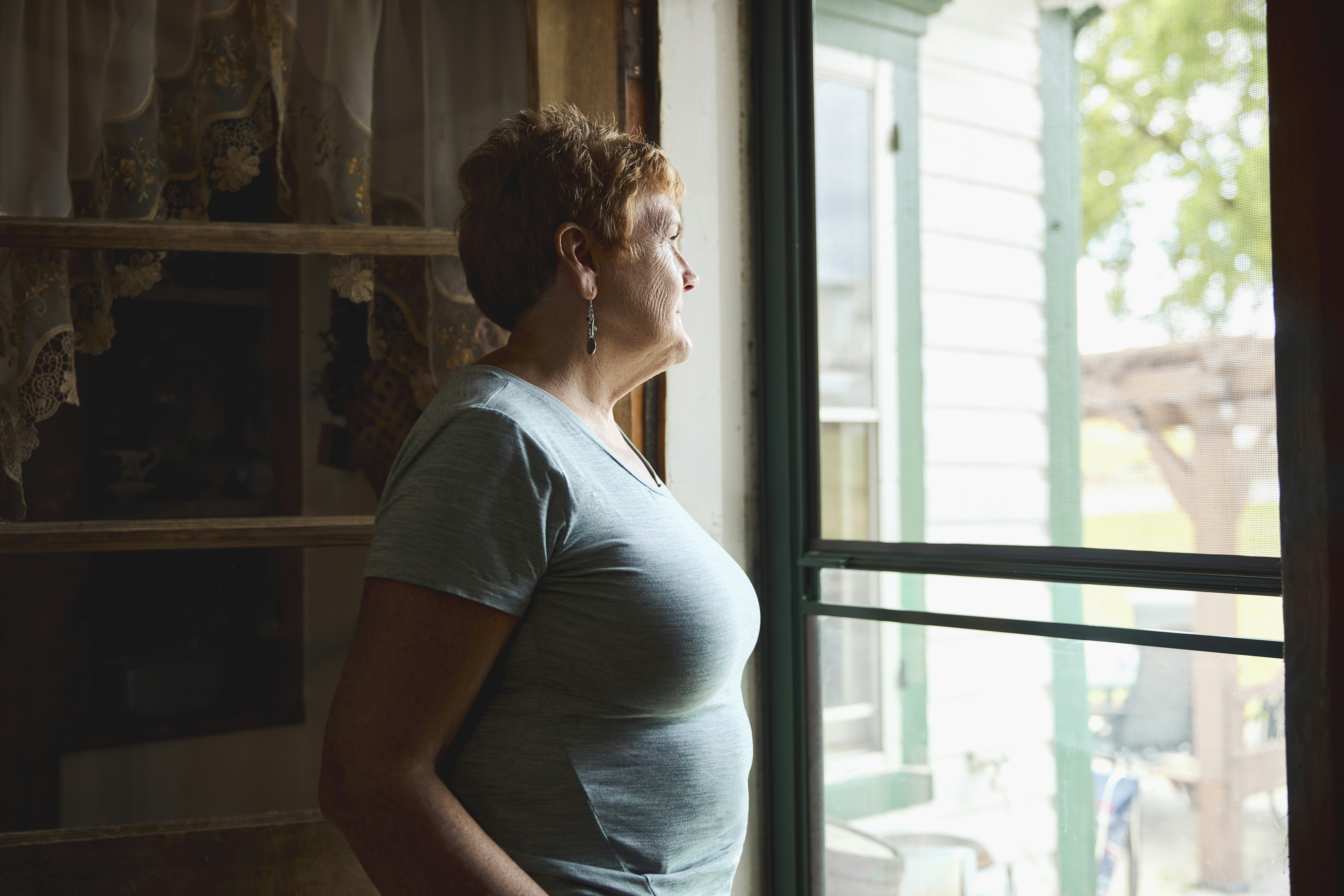 Woman looking out from a screen door