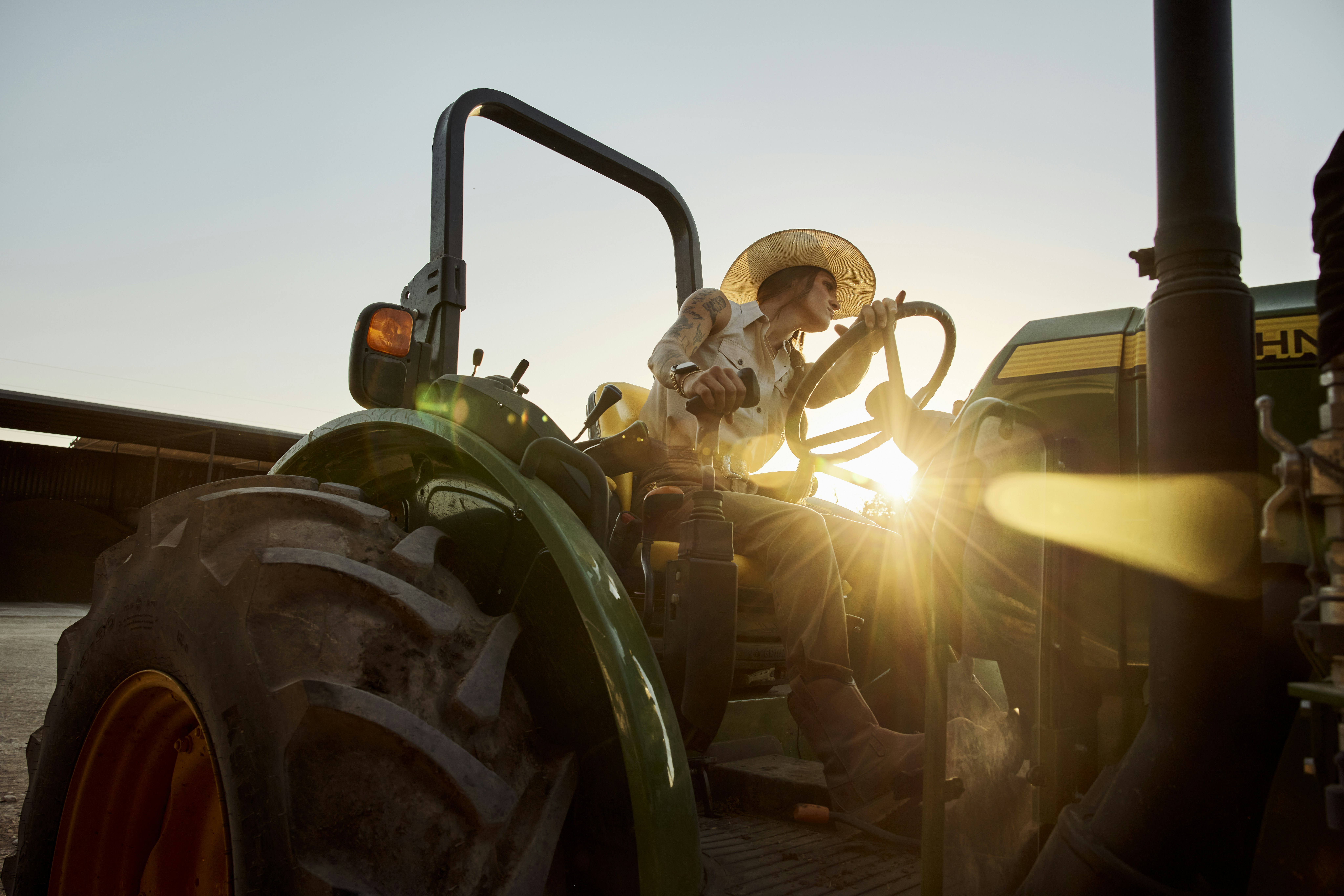 Woman on a tractor at sunrise. Texas, USA.