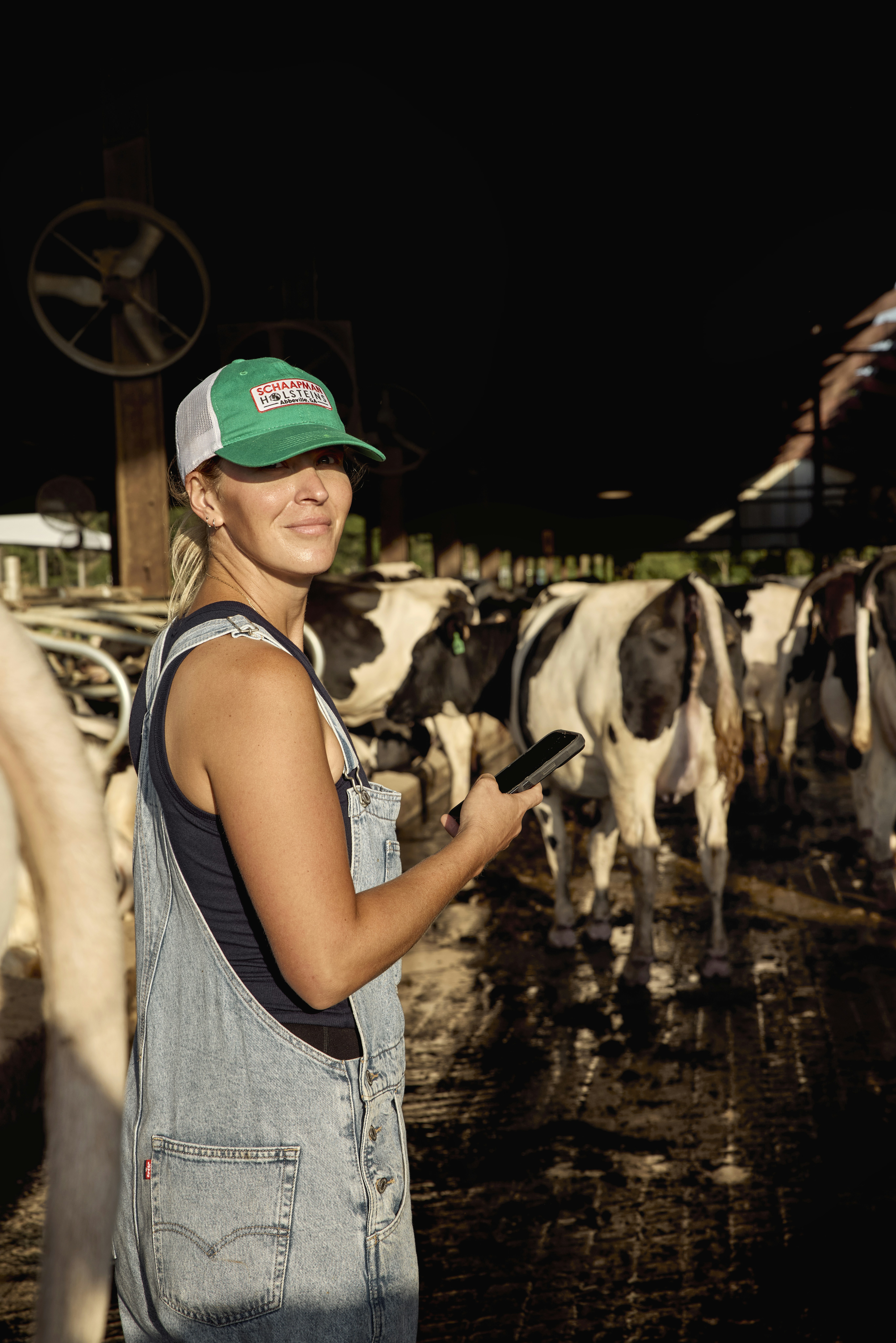 Woman holding a phone in a dairy barn