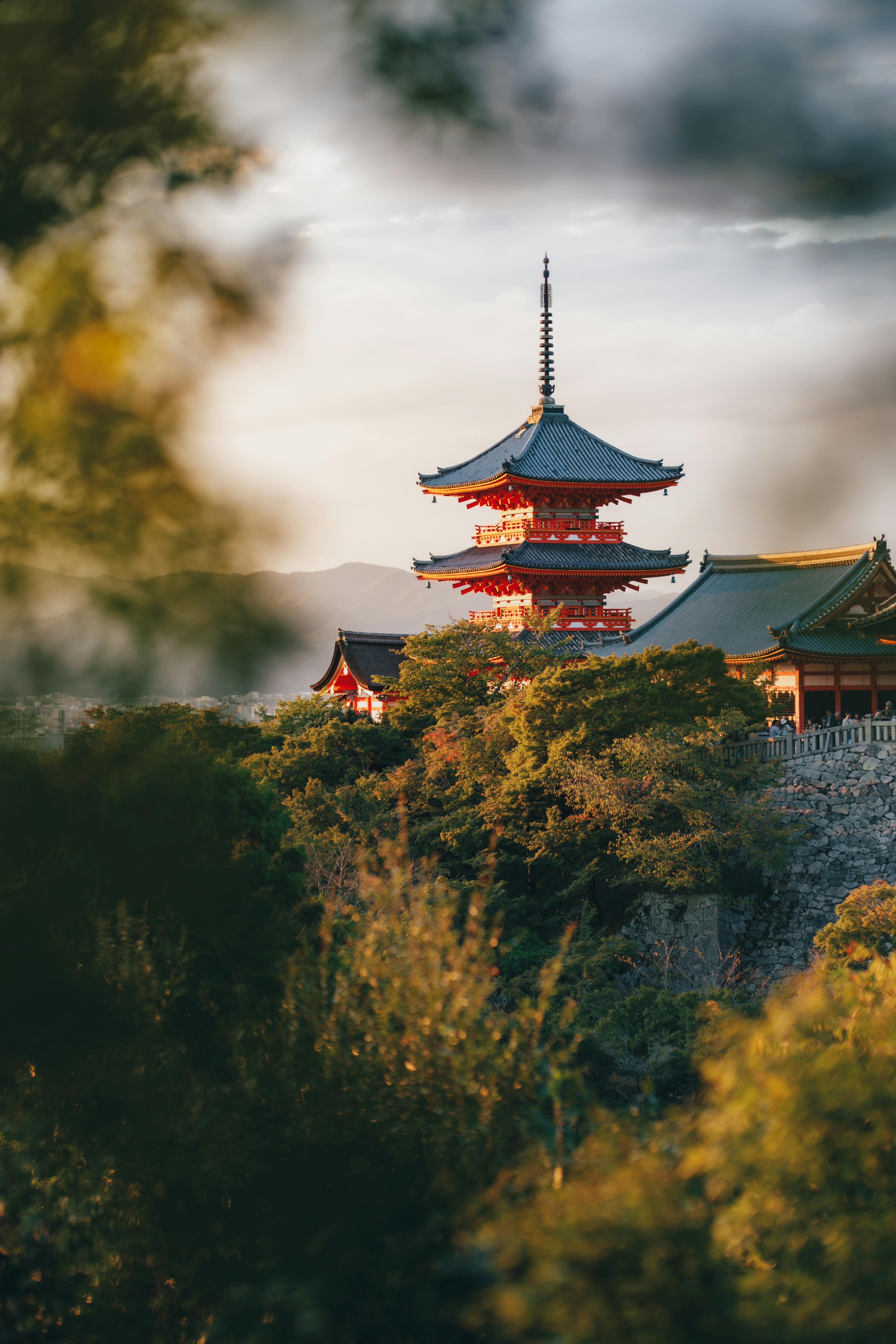 A red pagoda at Kiyomizu-dera temple in Kyoto surrounded by lush green trees