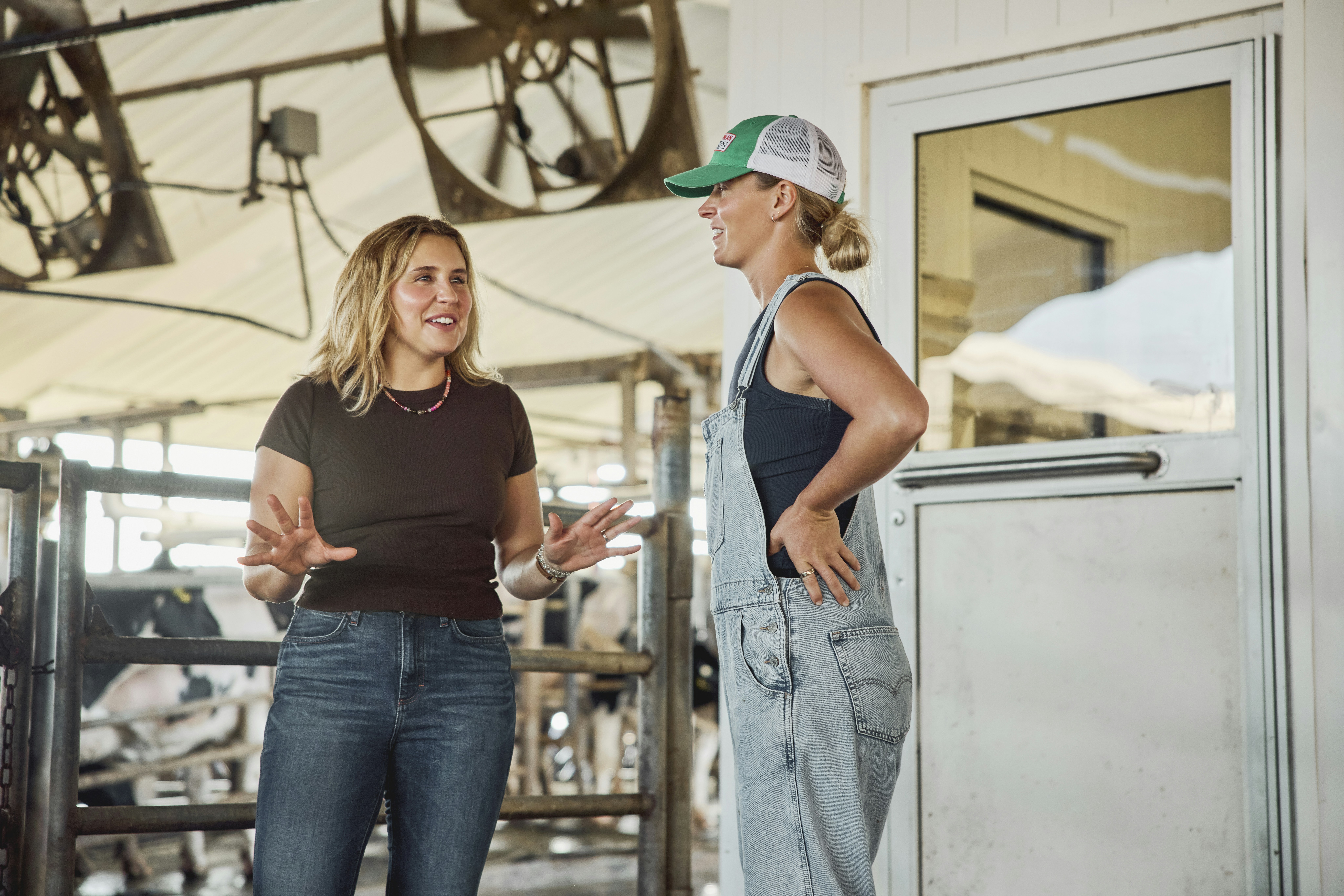 Two women talking inside a dairy barn. Georgia, USA.