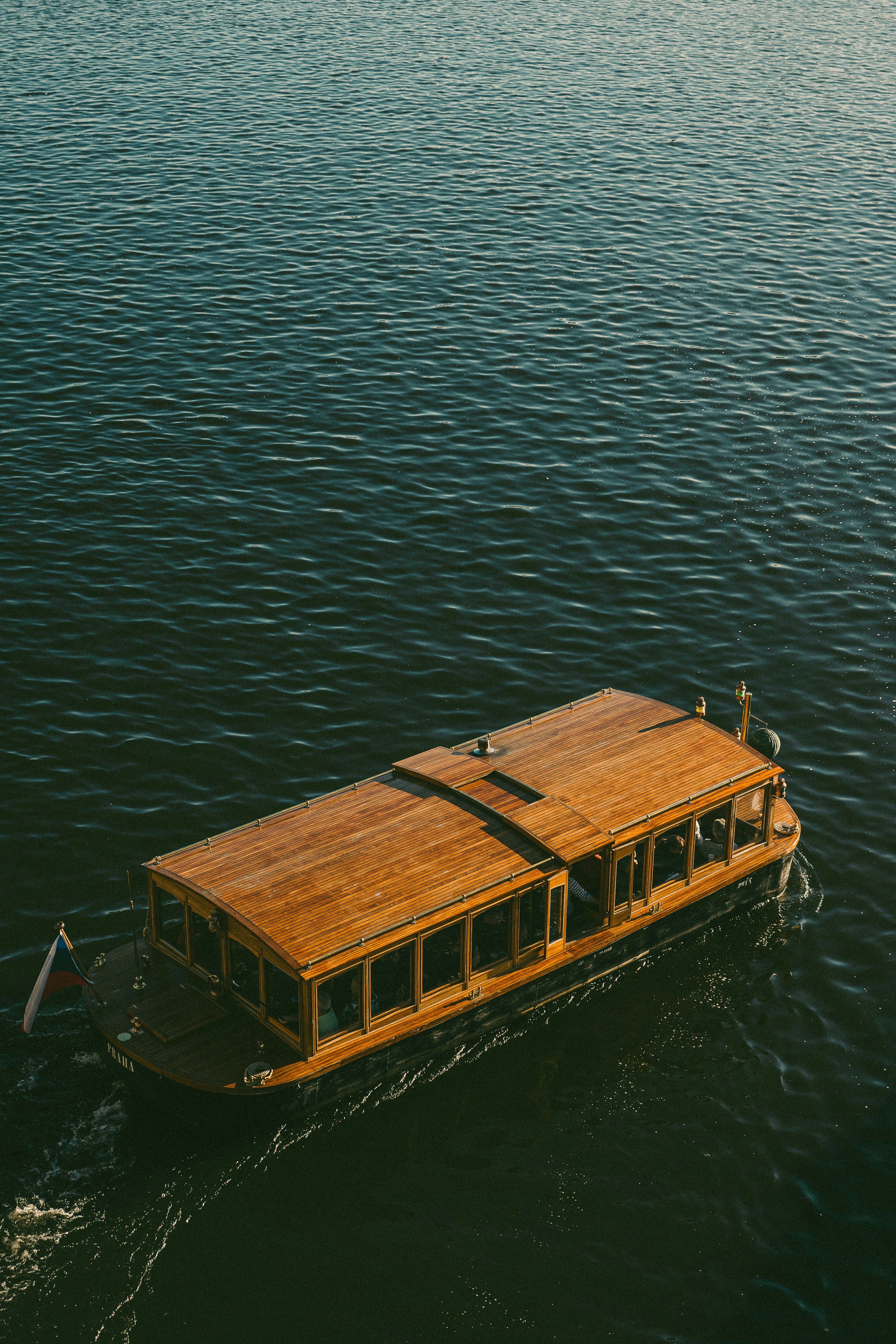 Bateau à coque et toit en bois naviguant sur une eau sombre, vu du dessus