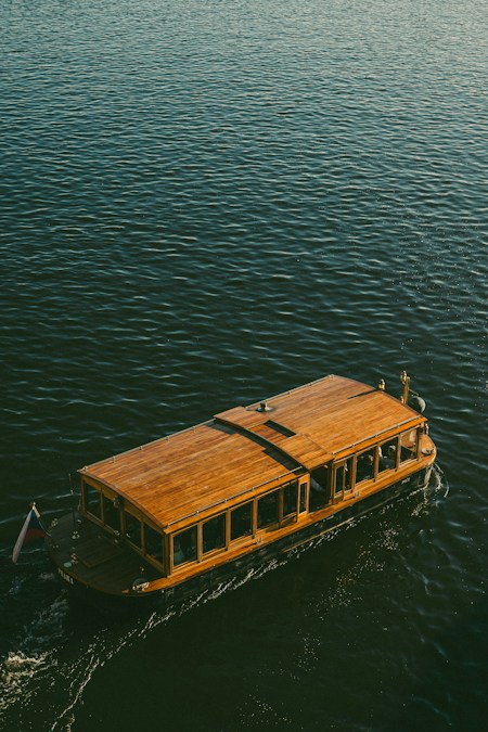 Bateau à coque et toit en bois naviguant sur une eau sombre, vu du dessus