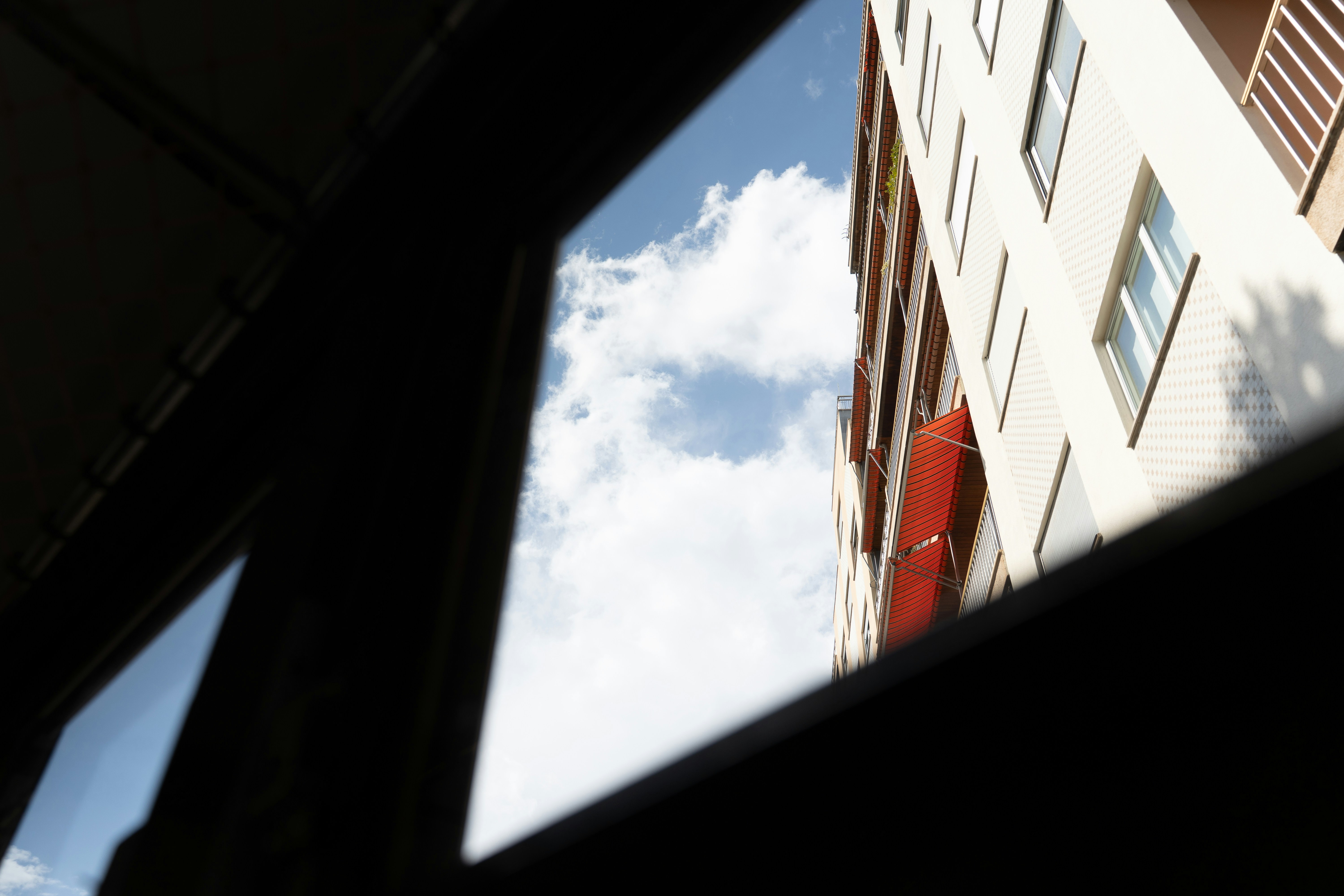 A tall apartment building with red awnings against a bright blue sky