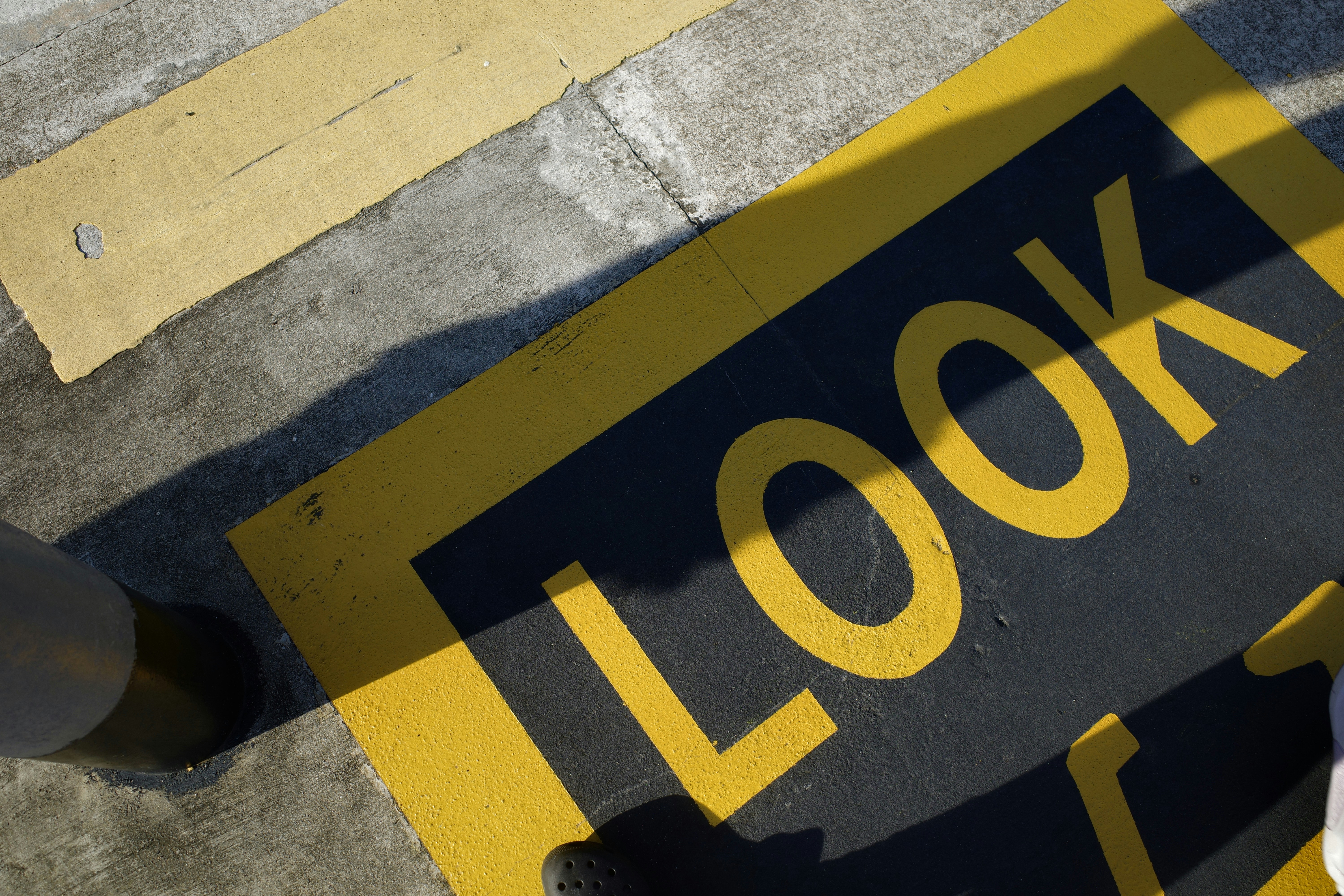 The word LOOK painted in yellow on a black square on a concrete pavement