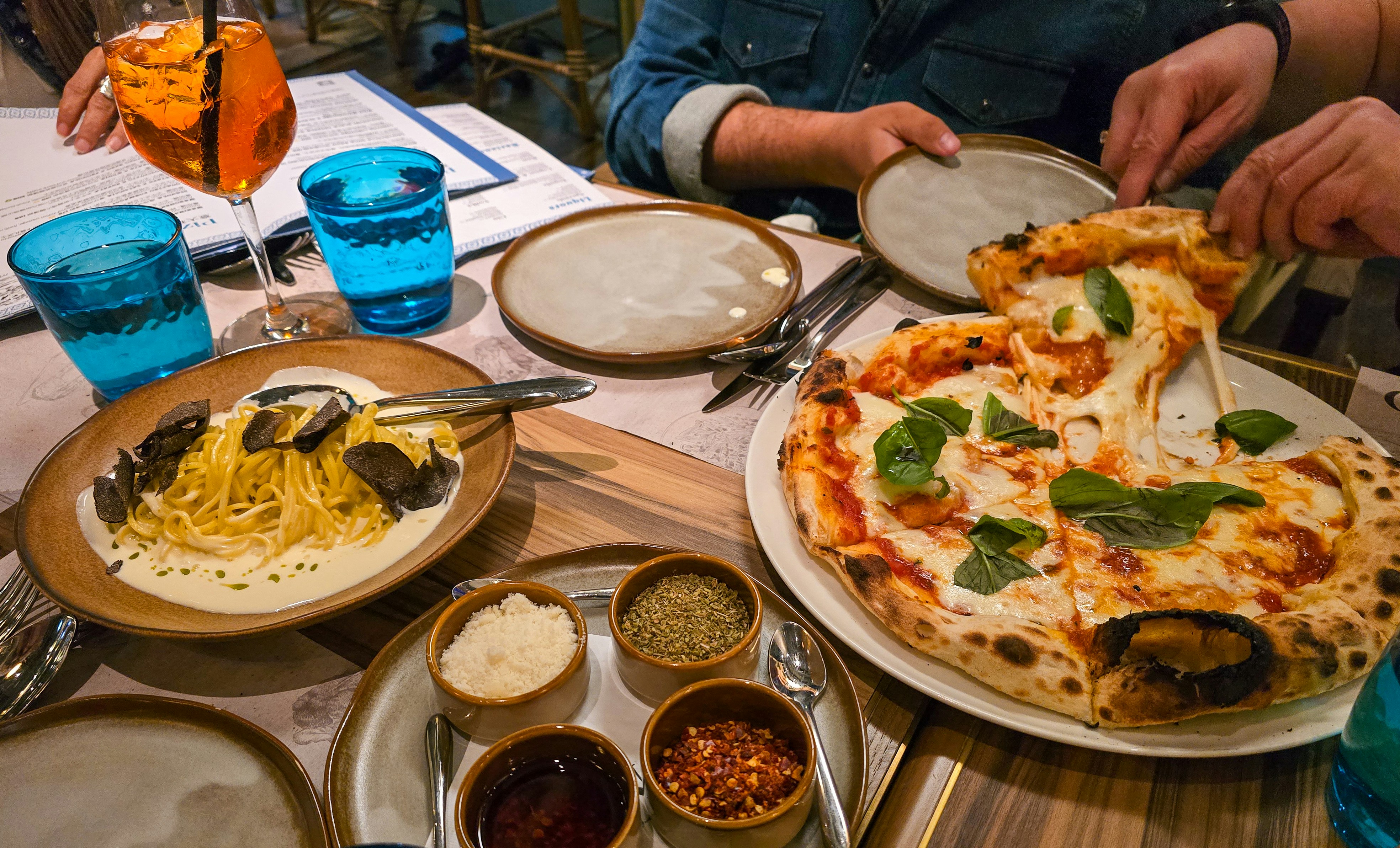Friends sharing plates of pizza and pasta around a restaurant table