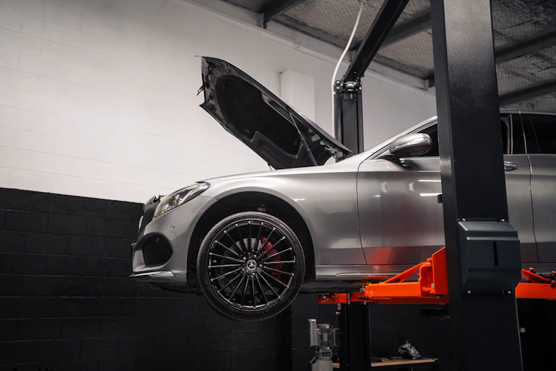 Silver car on a hydraulic lift with the bonnet open for a pre-test inspection in Sharjah
