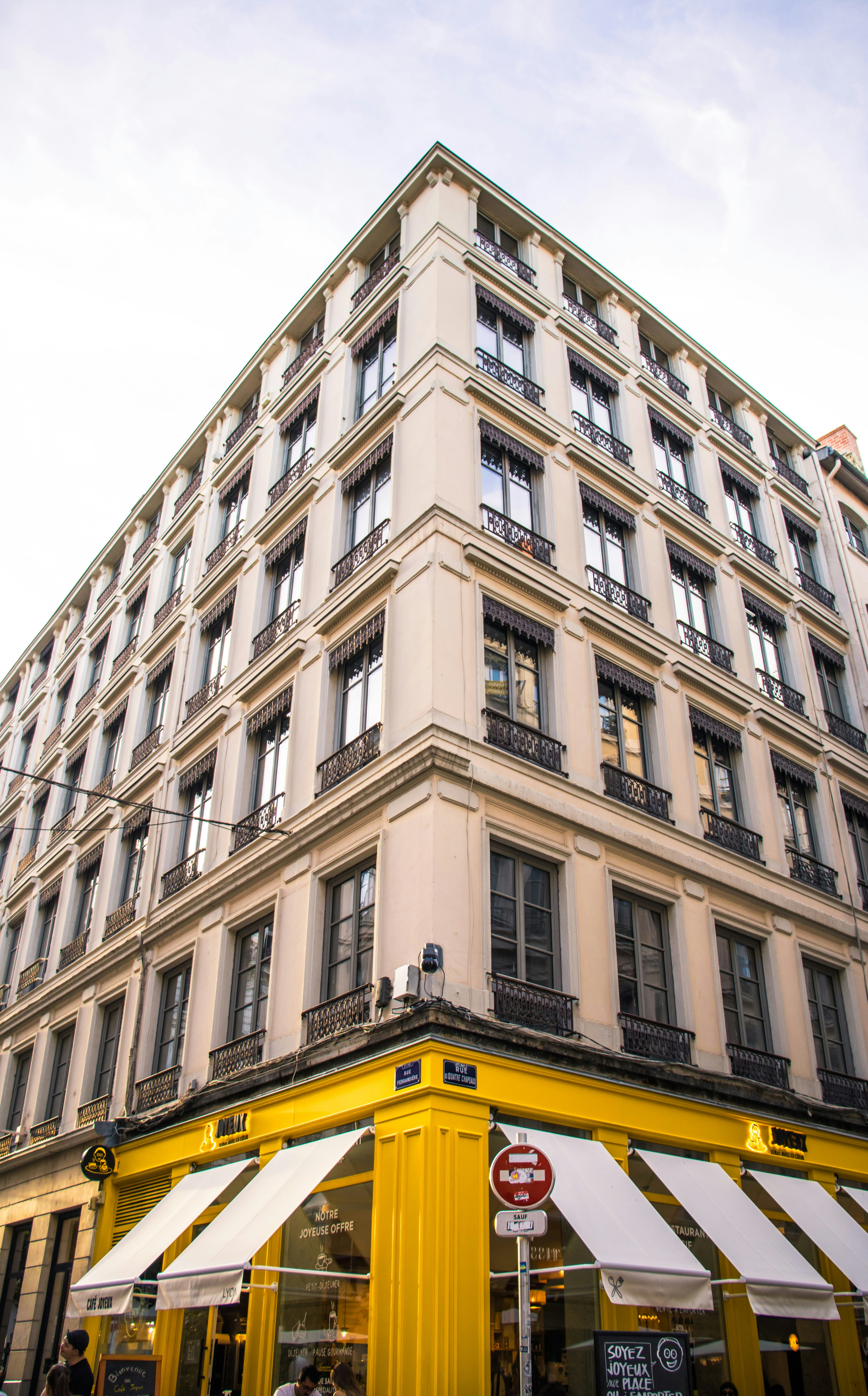 Um prédio de esquina com uma vitrine amarela brilhante e toldos brancos em Lyon