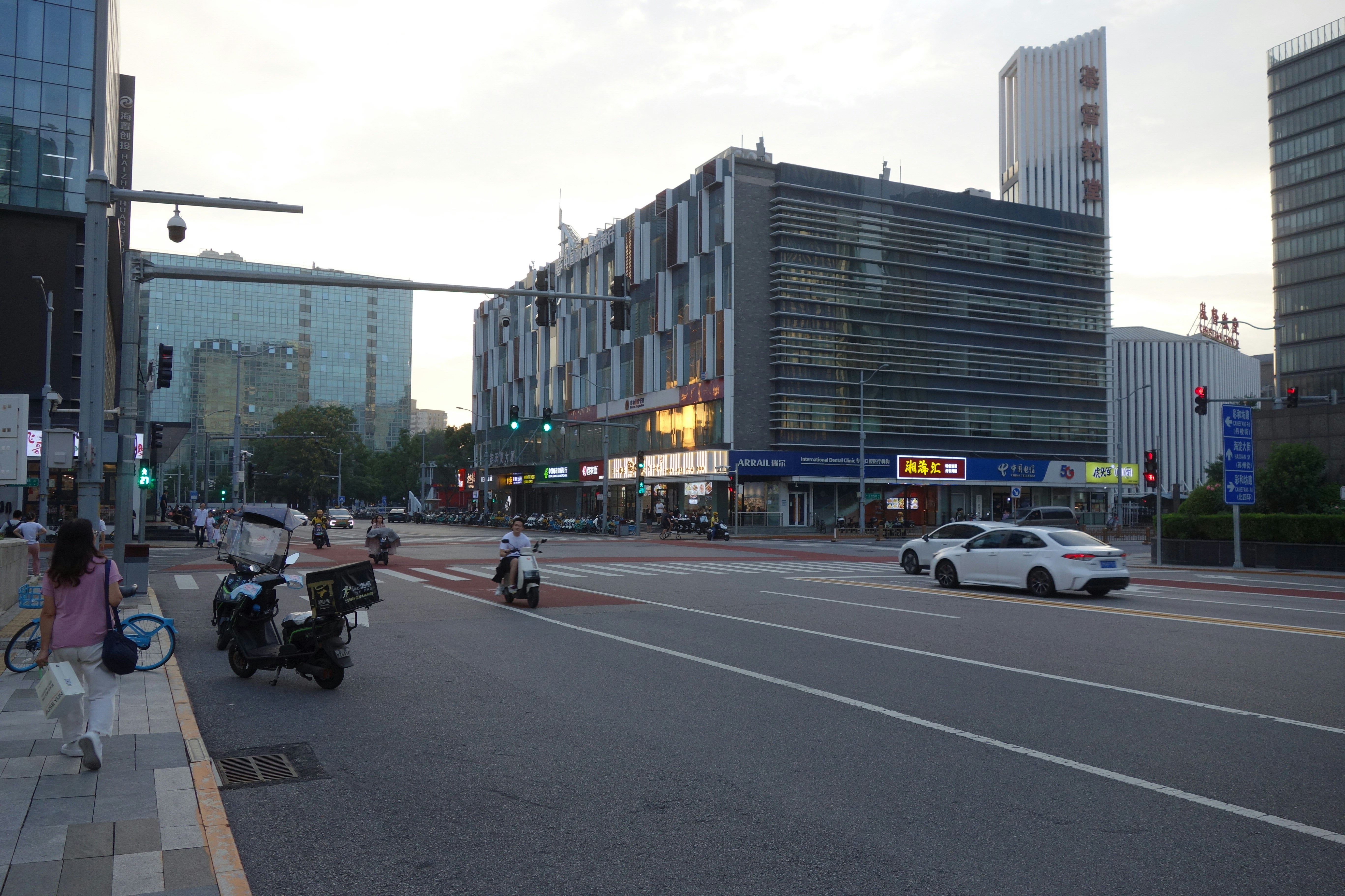 A person walking on a sidewalk beside a busy city intersection with vehicles