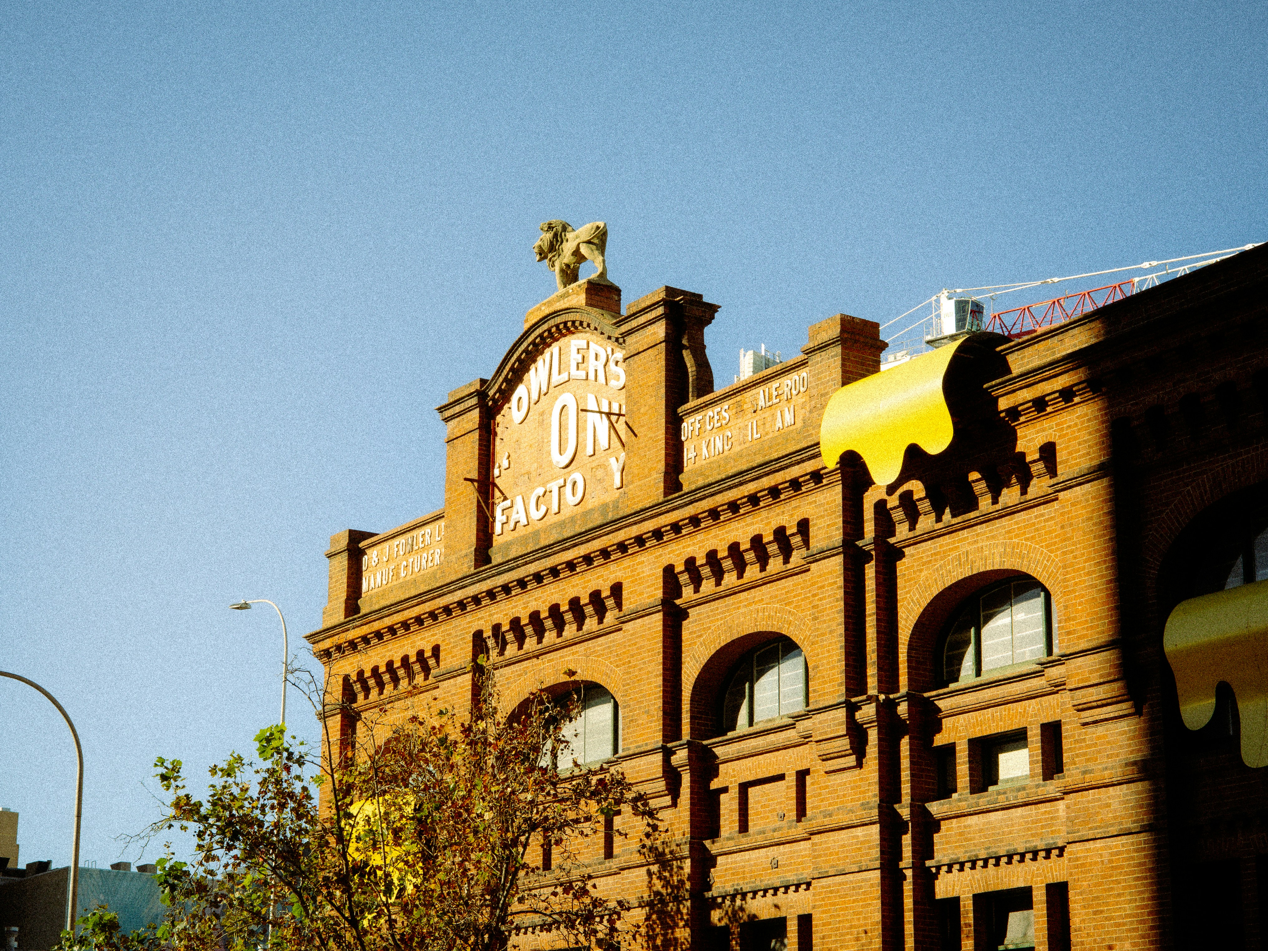 A brick building with a lion statue on the roof under a blue sky