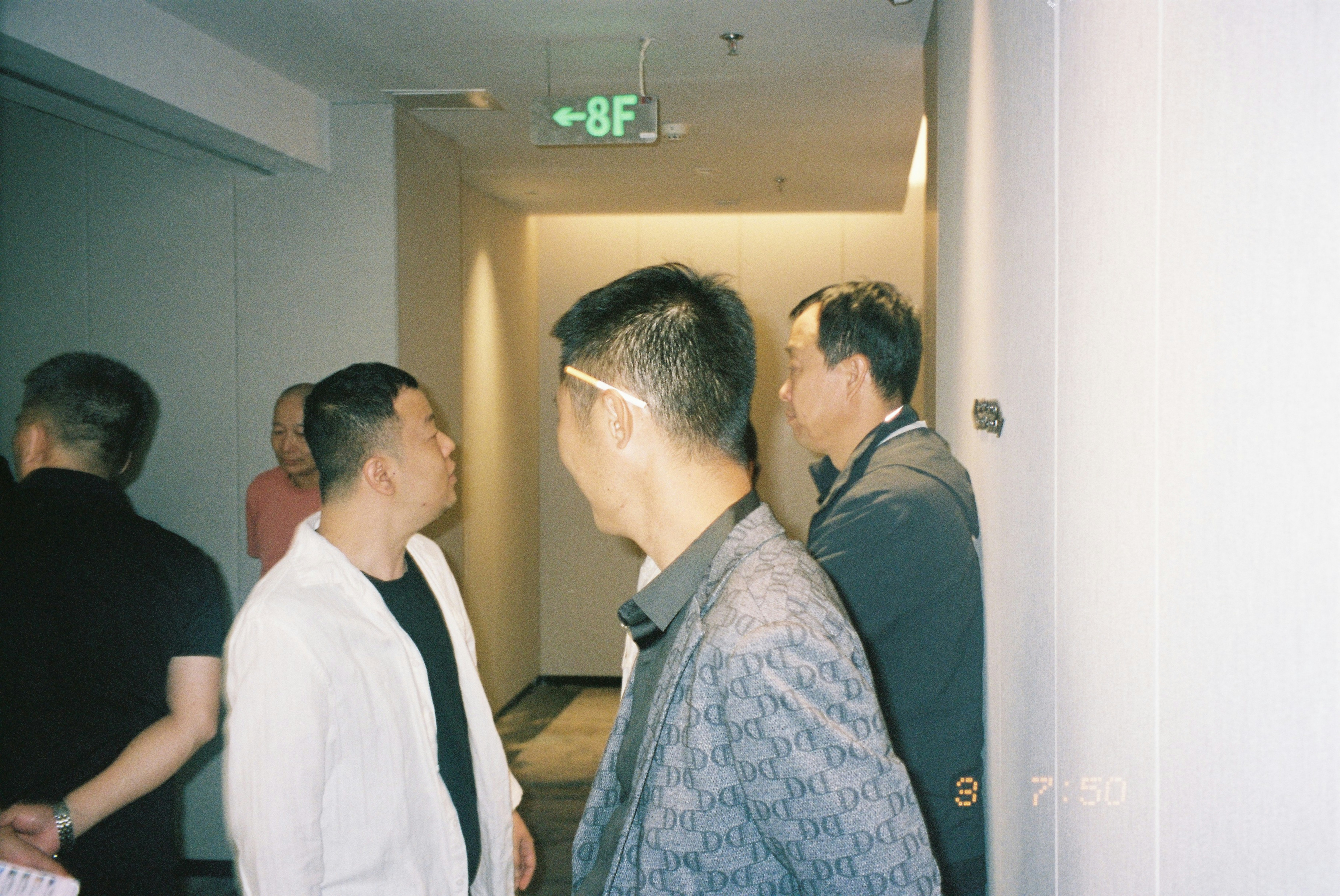 A group of men in a hallway with an 8F sign above