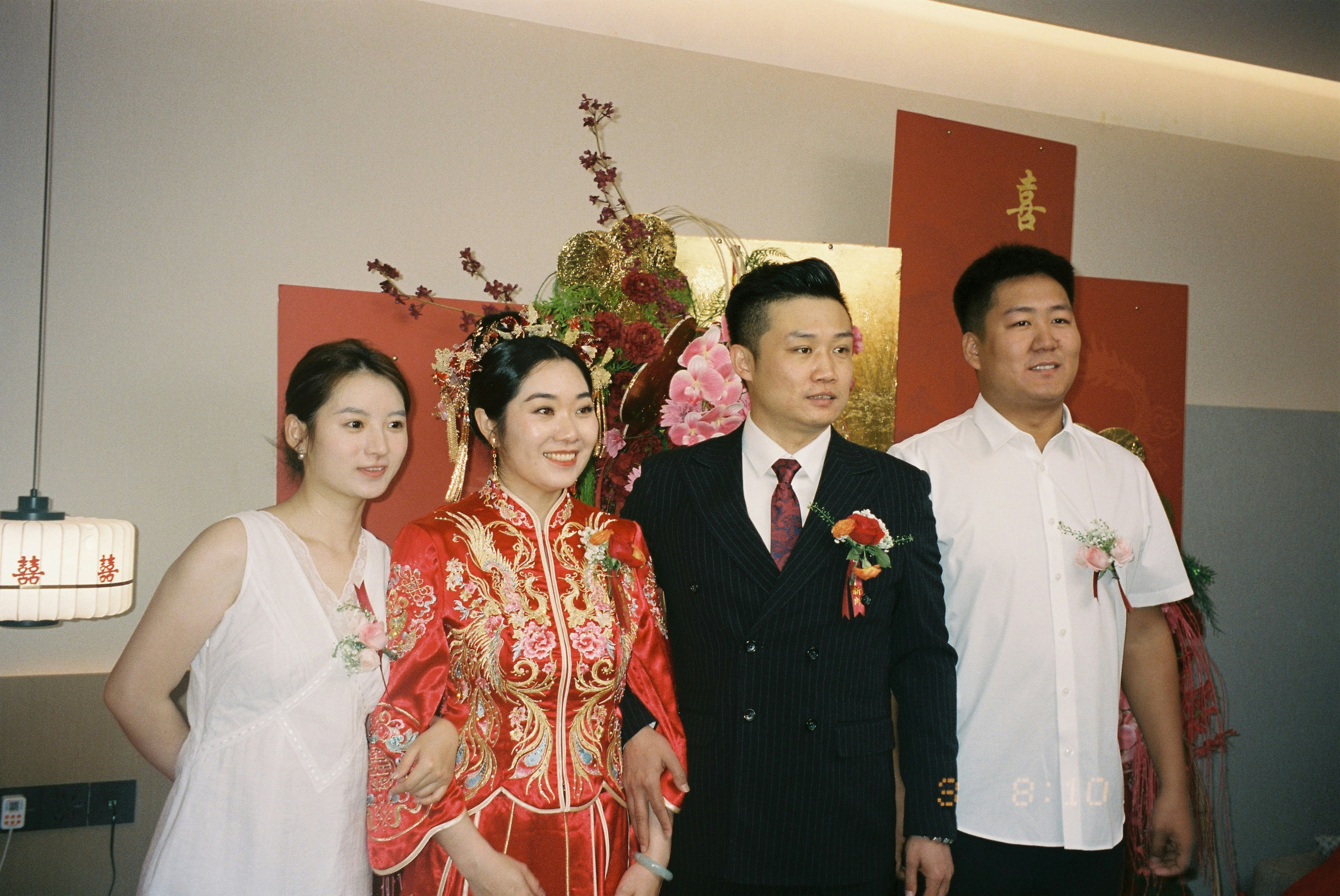 A bride in a red traditional dress and groom in a suit with two guests
