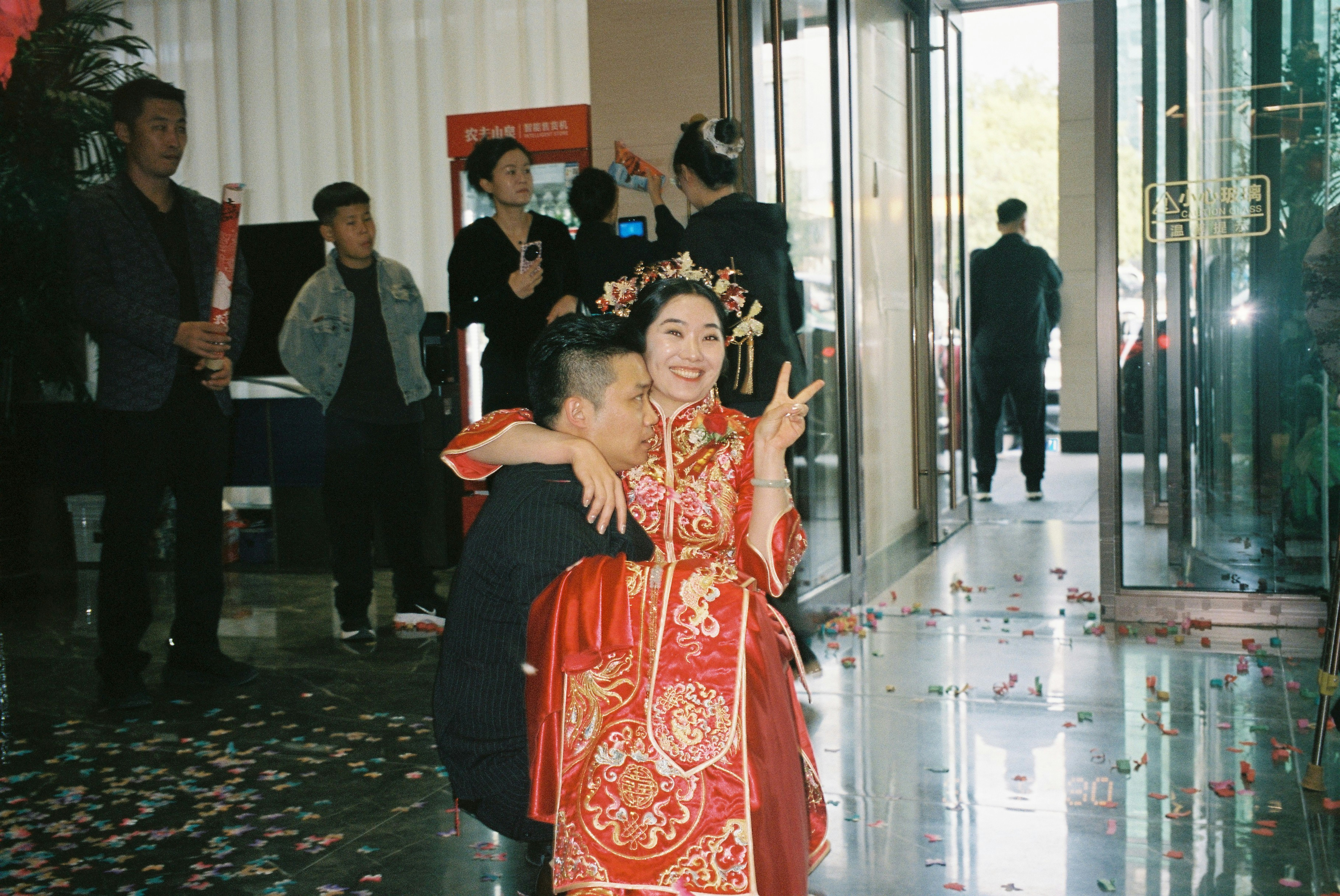 A man carrying a woman in a traditional red wedding dress indoors