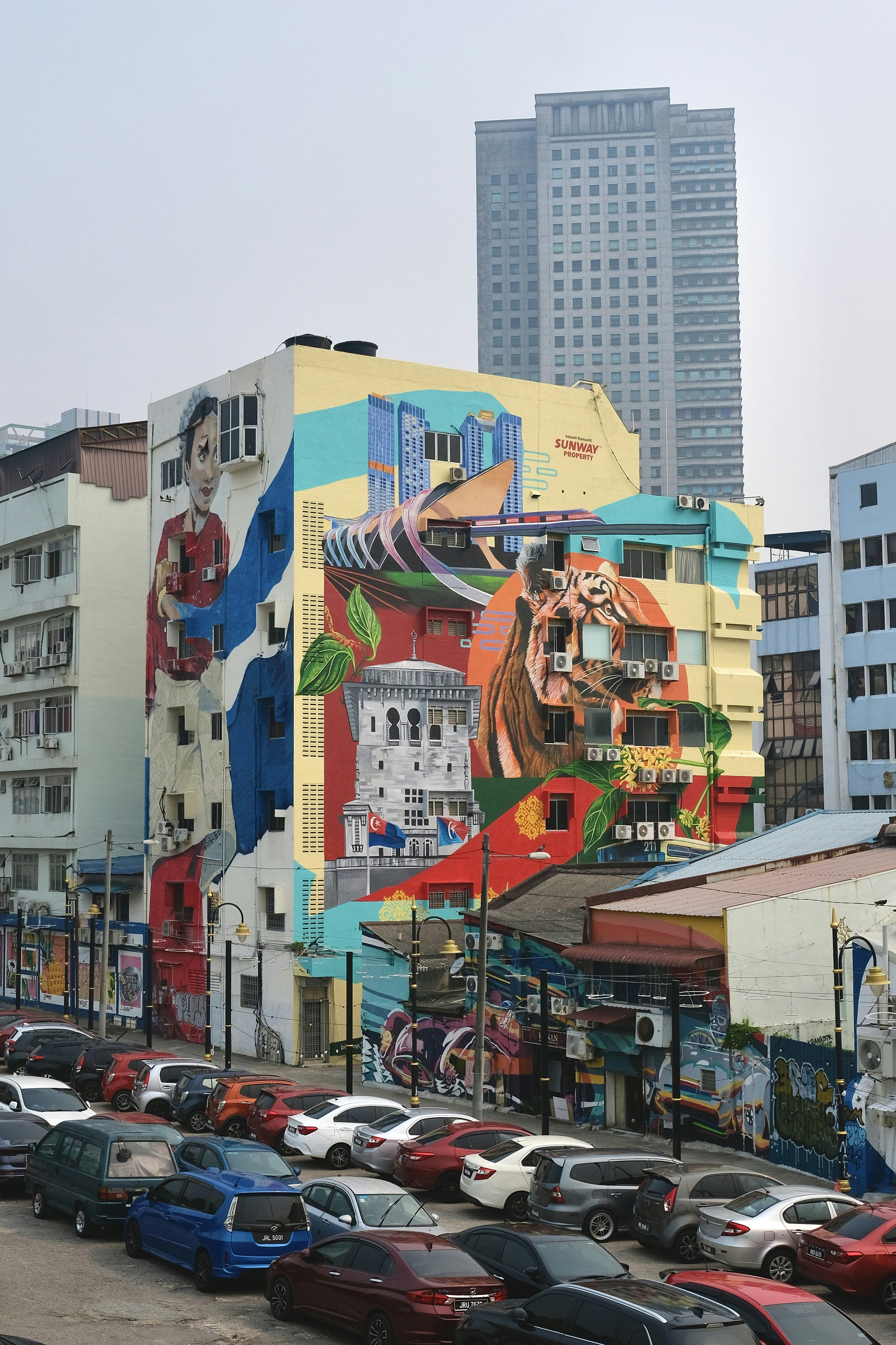 A large colorful mural on a building facade featuring a tiger and architecture