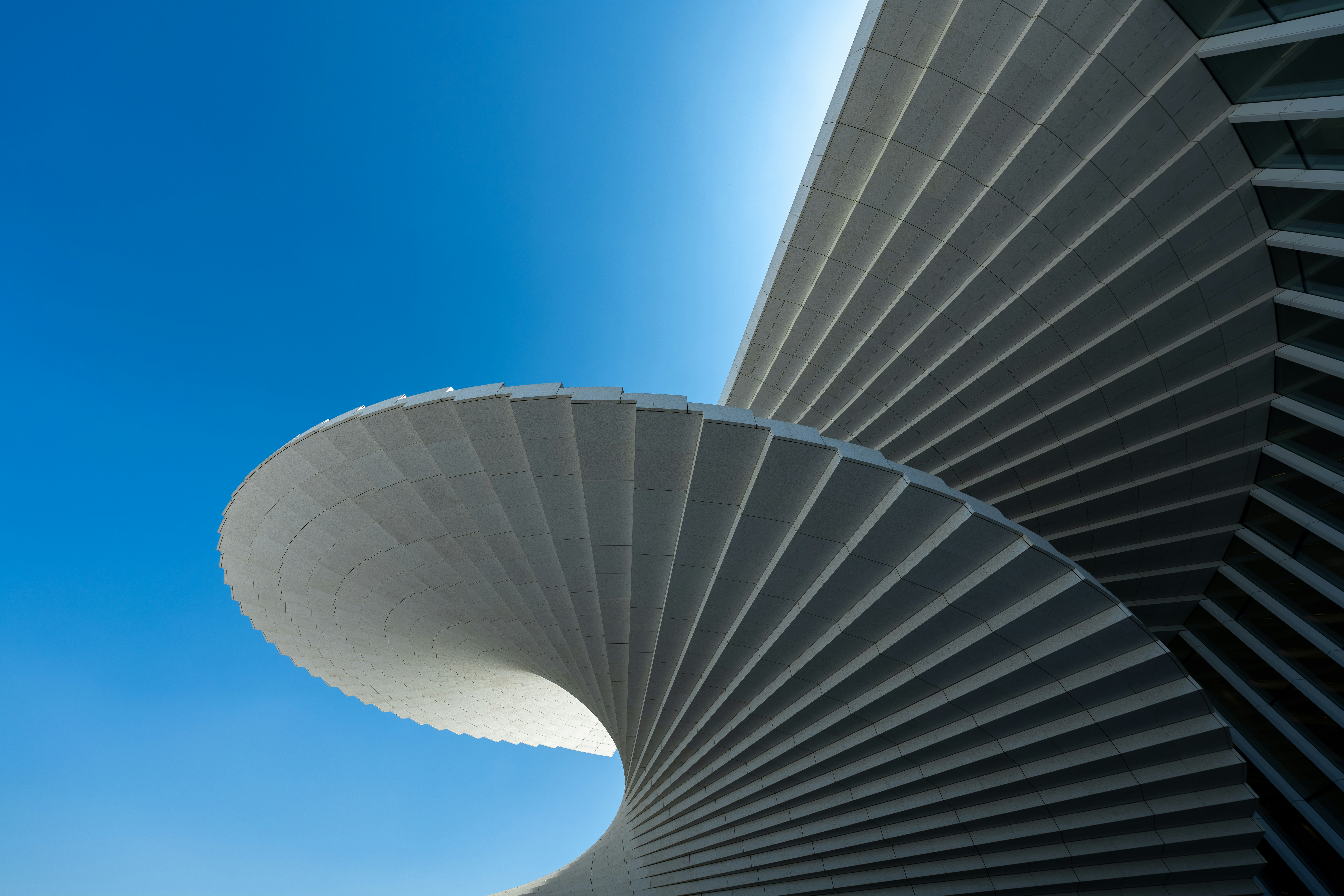 A spiraling white architectural structure against a clear blue sky