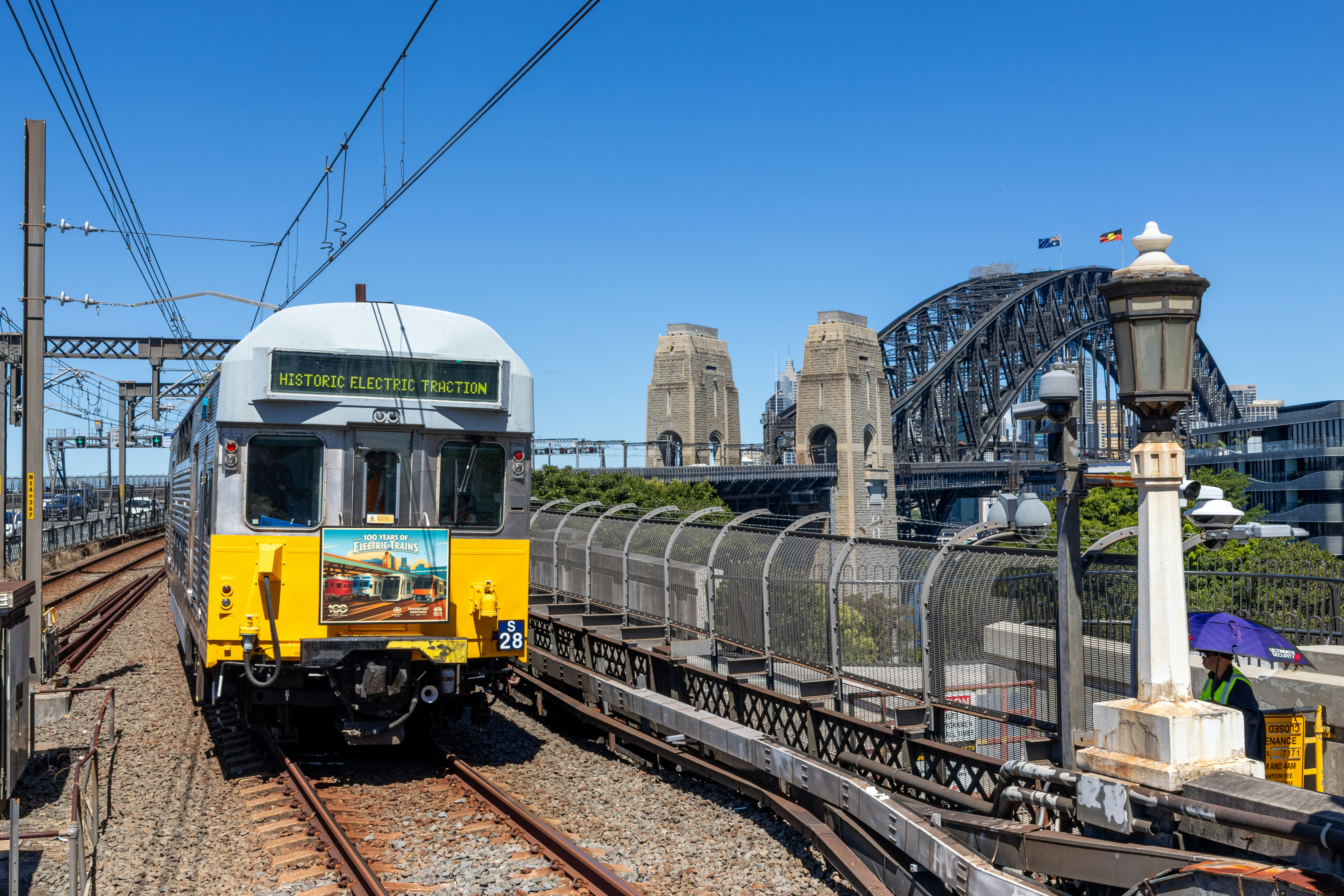 A vintage electric train on tracks near the Sydney Harbour Bridge in Sydney