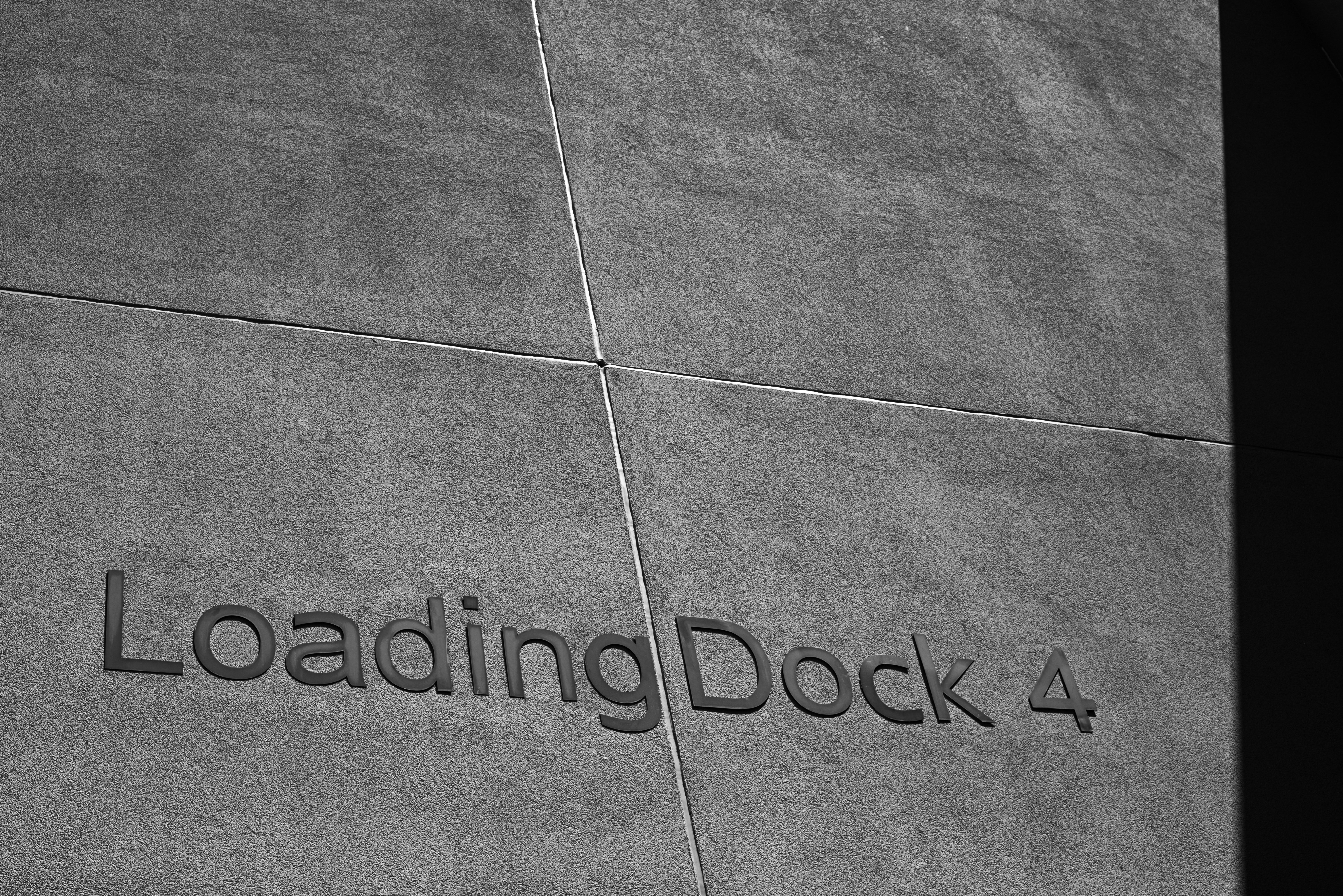 A black and white view of a concrete wall with the text Loading Dock 4