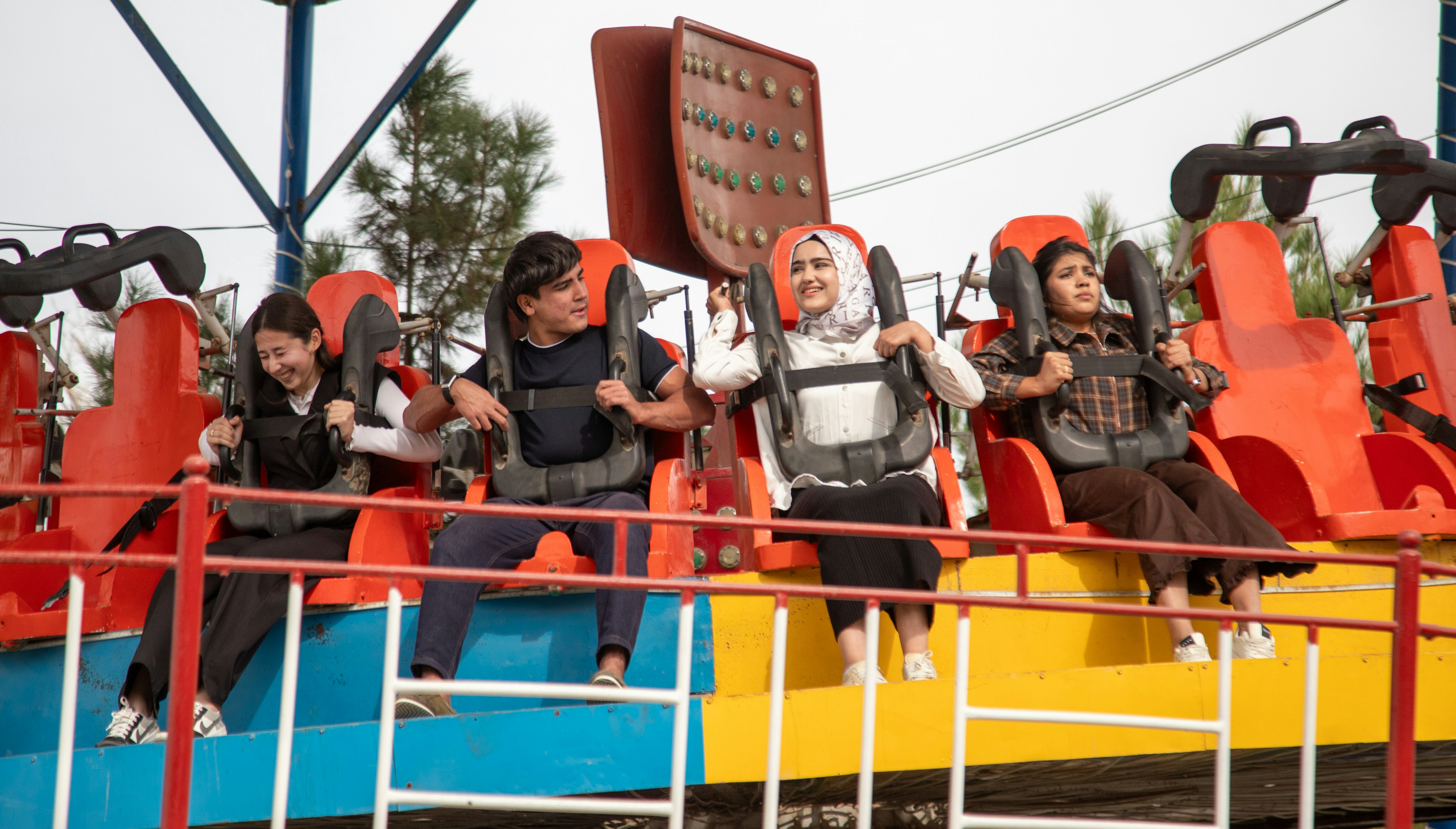 Four people sitting in orange seats on an amusement park ride