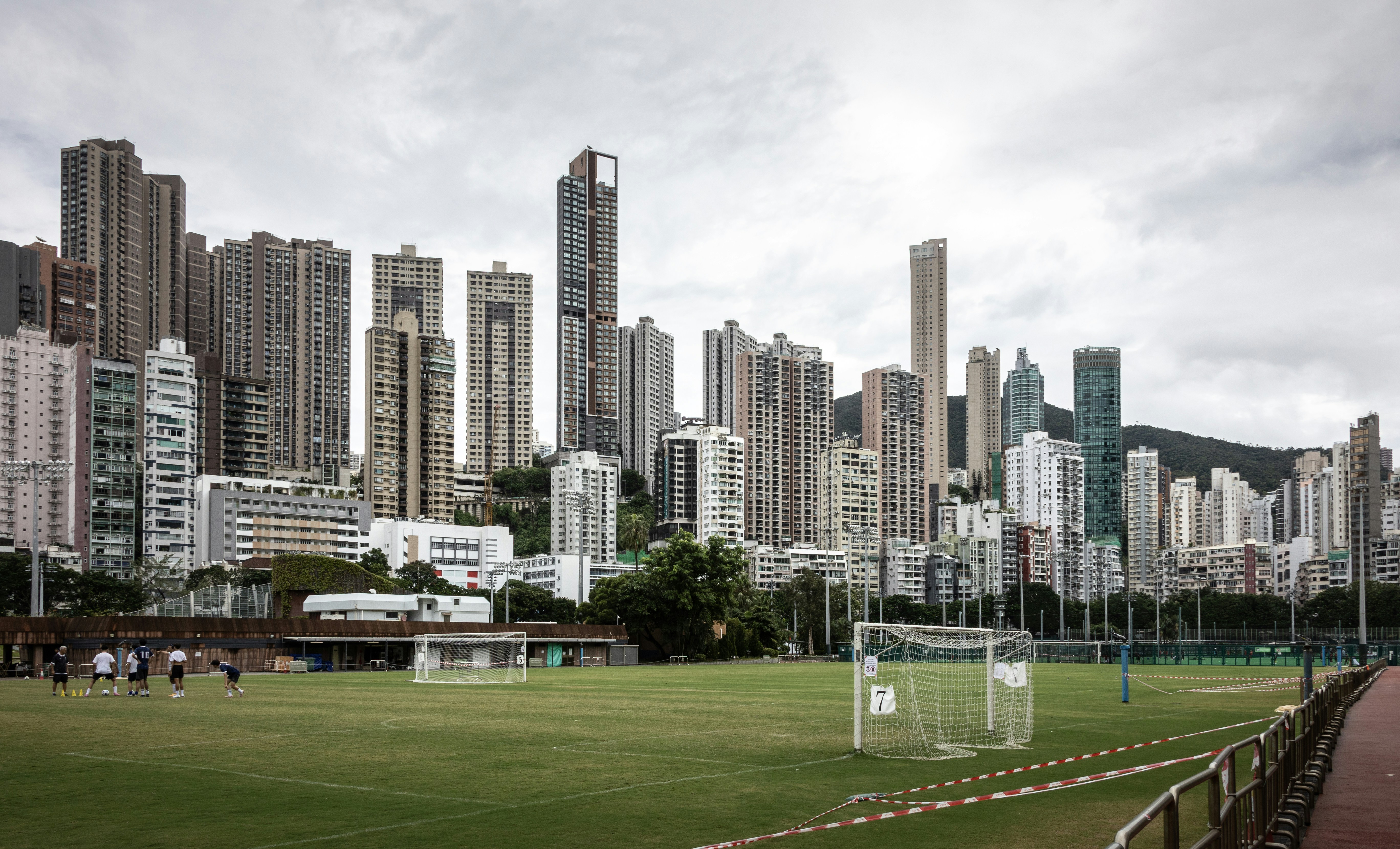 Um grupo de pessoas em um campo de futebol diante de um denso horizonte de Hong Kong